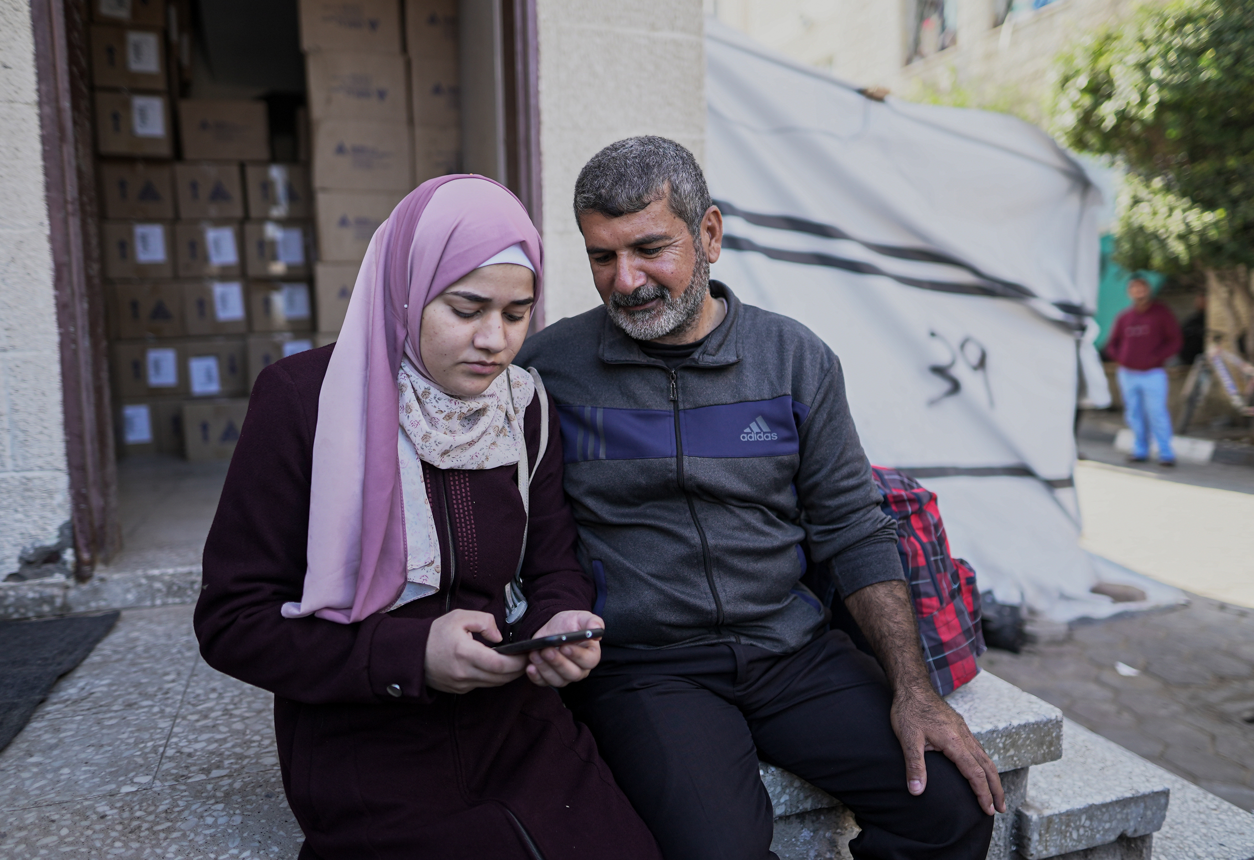 Sawsan Abu Odeh and her father, Khaled, sit outside Al-Aqsa Martyrs Hospital waiting for the ambulance that will take her to the Rafah border crossing with Egypt to be reunited with her twin baby girls