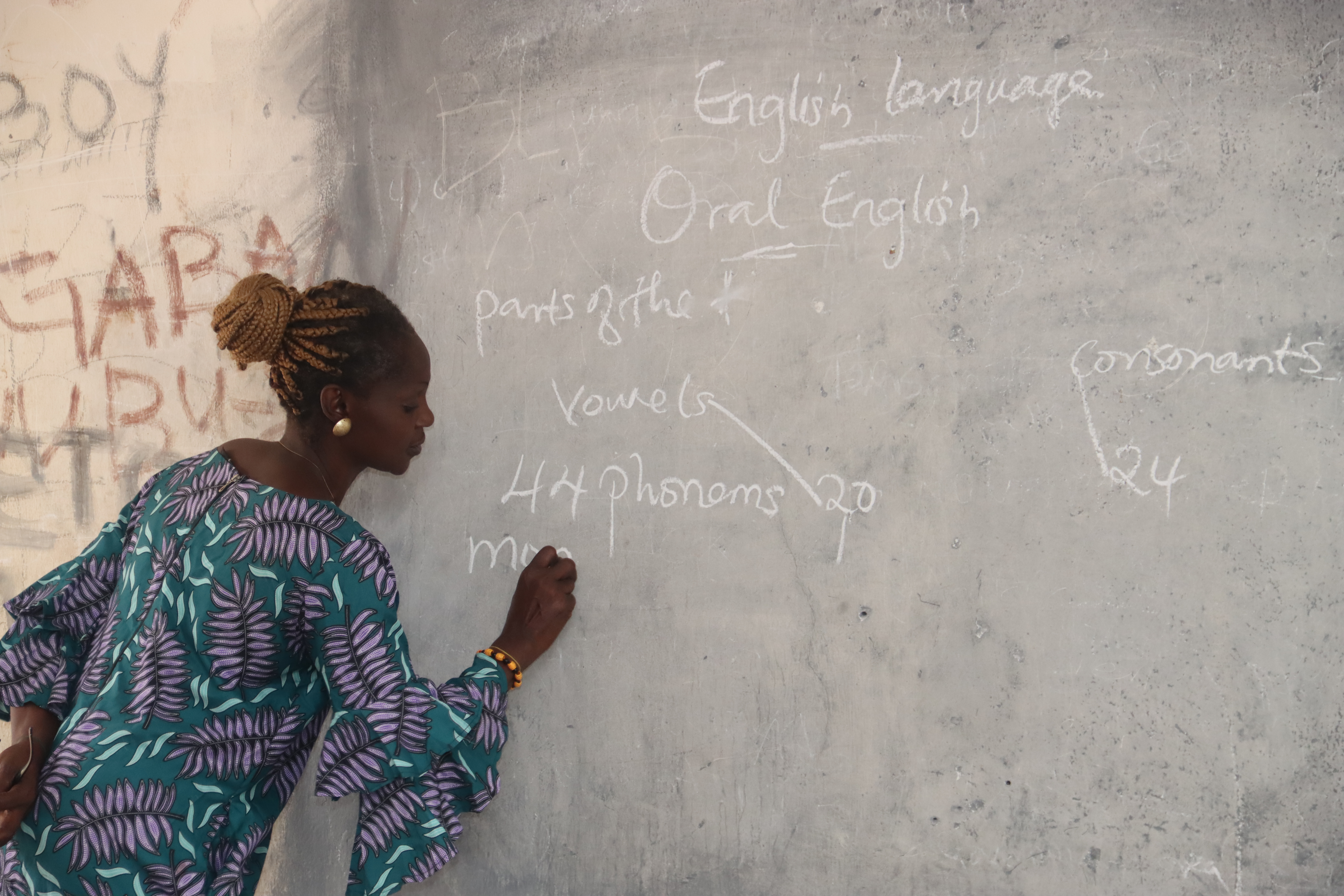 A photo of Comfort Ullah Solomon writing on a blackboard.