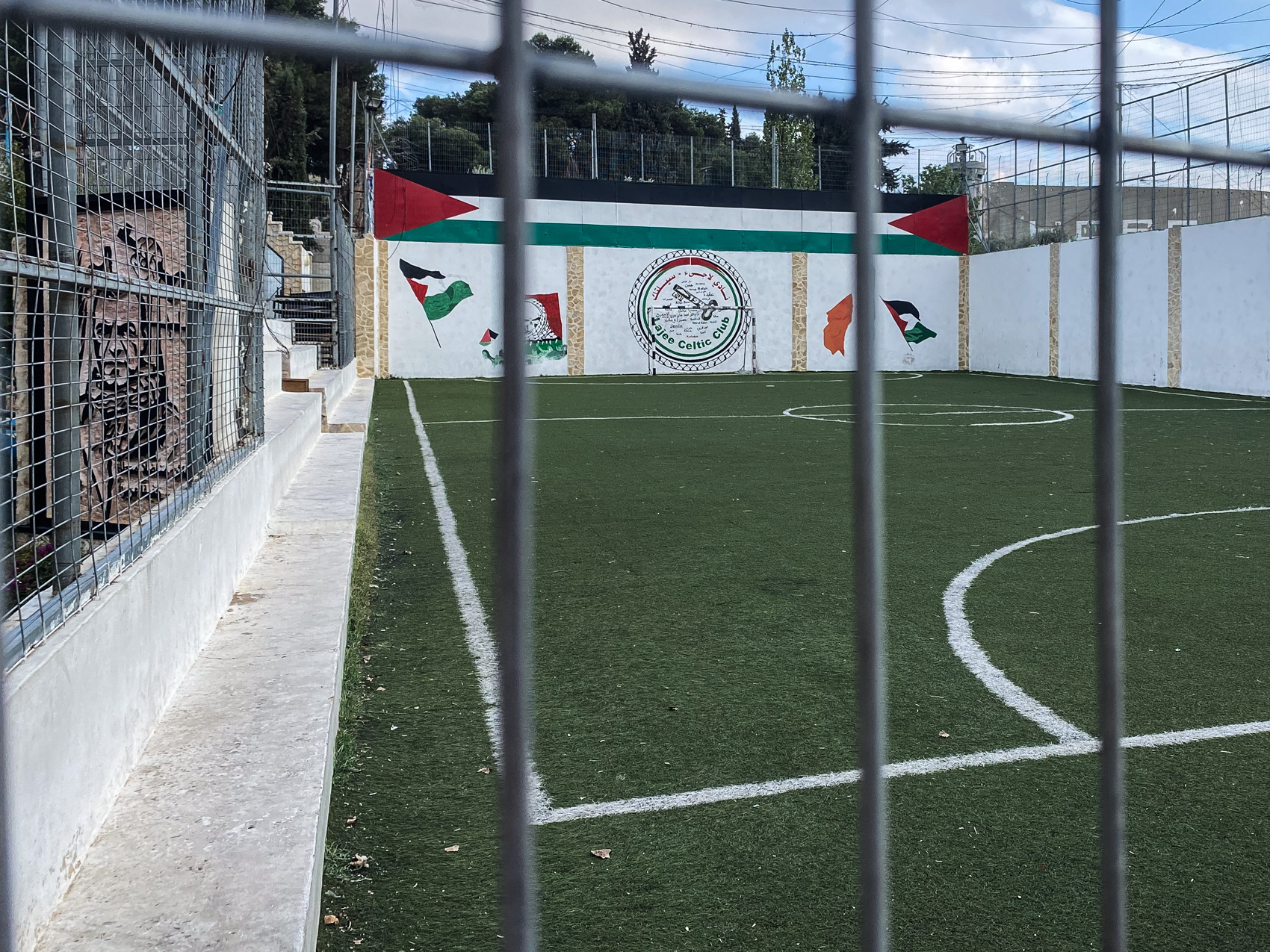 A view of an empty Lajee Celtic pitch with Palestinian flag murals on the far wall