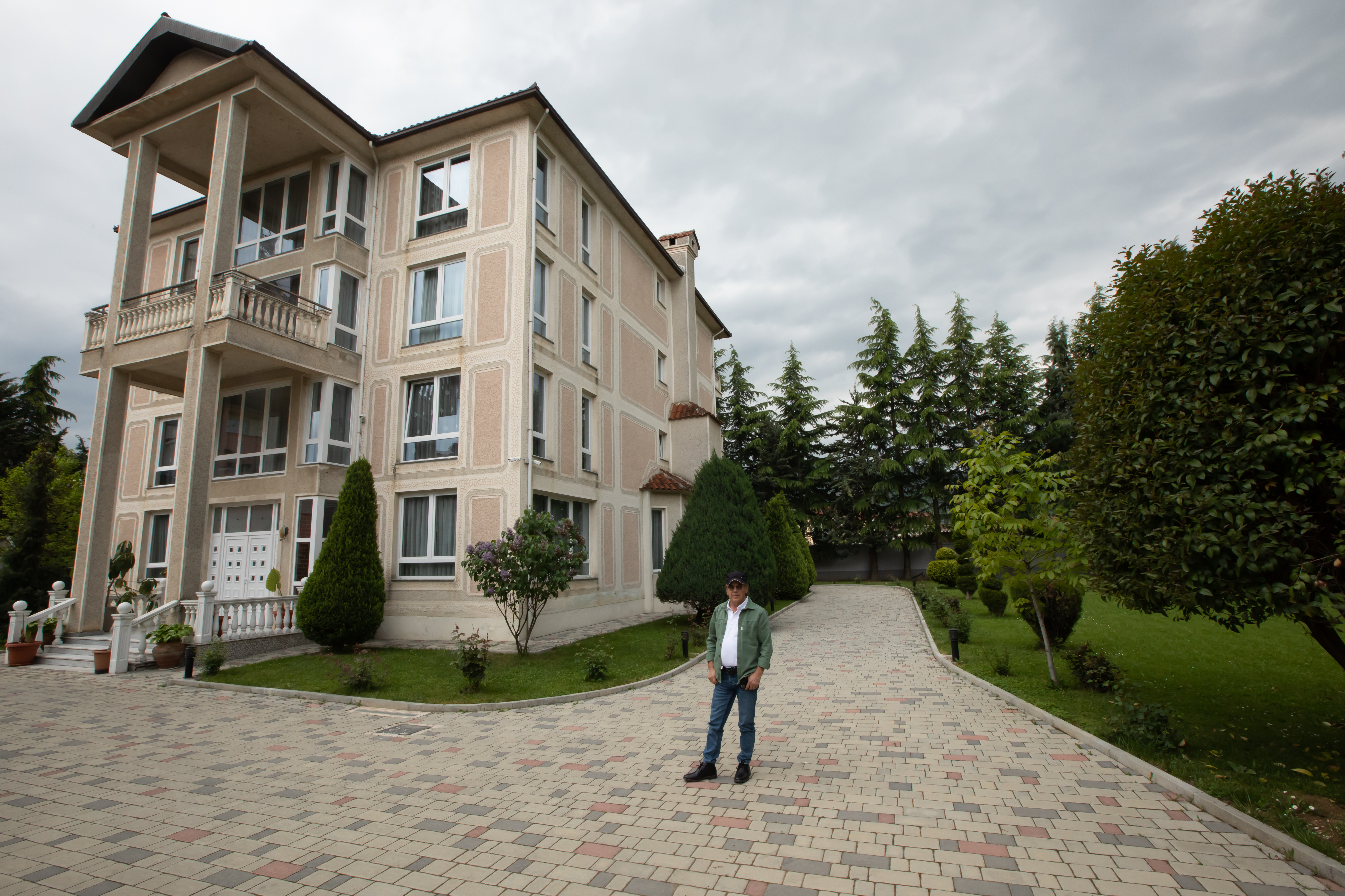 Bajram Fezollari stands in front of his villa in Pogradec, where he now lives