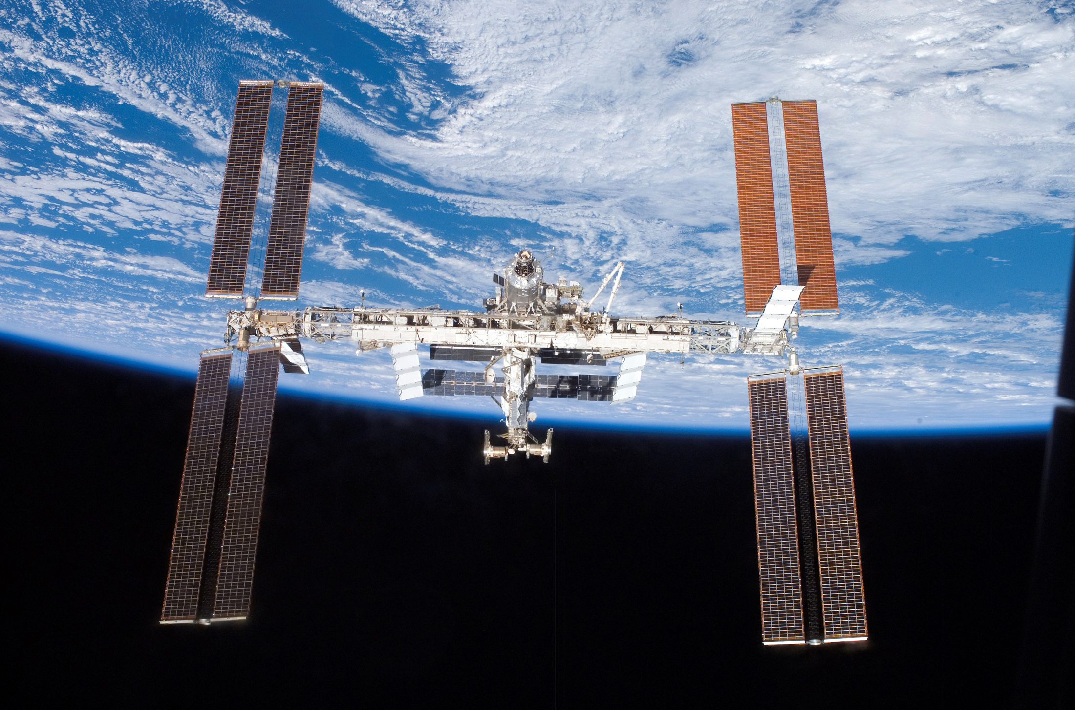 Backdropped by the blackness of space and Earth's horizon, the International Space Station moves away from the Space Shuttle Atlantis in this digital photograph taken by an Atlantis crew member June 19, 2007