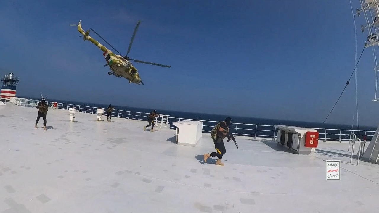 Houthi military helicopter hovers over the Galaxy Leader cargo ship as Houthi fighters walk on the ship's deck in the Red Sea in this photo released November 20, 2023