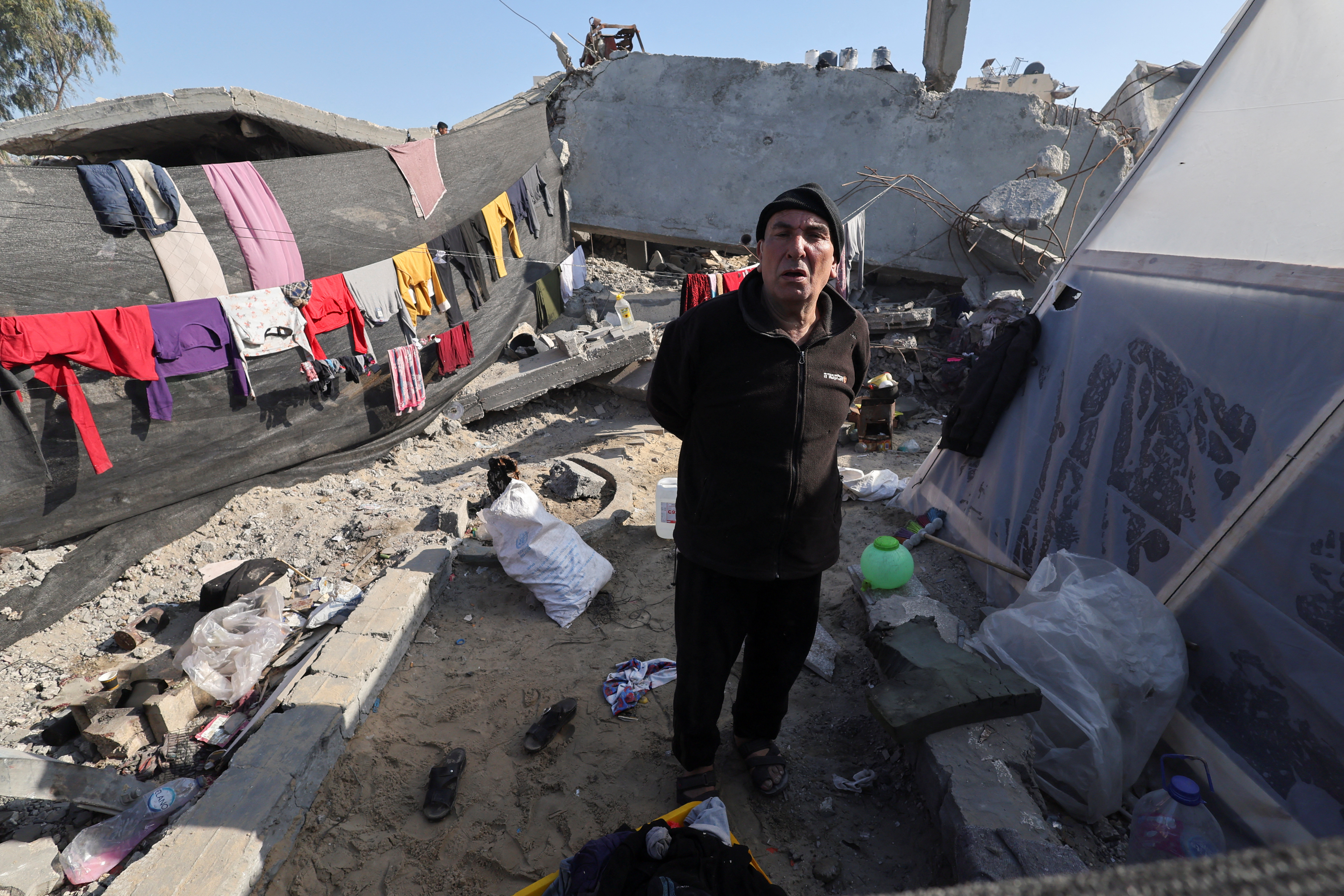 A displaced Palestinian man stands in a tent encampment for displaced people in Gaza
