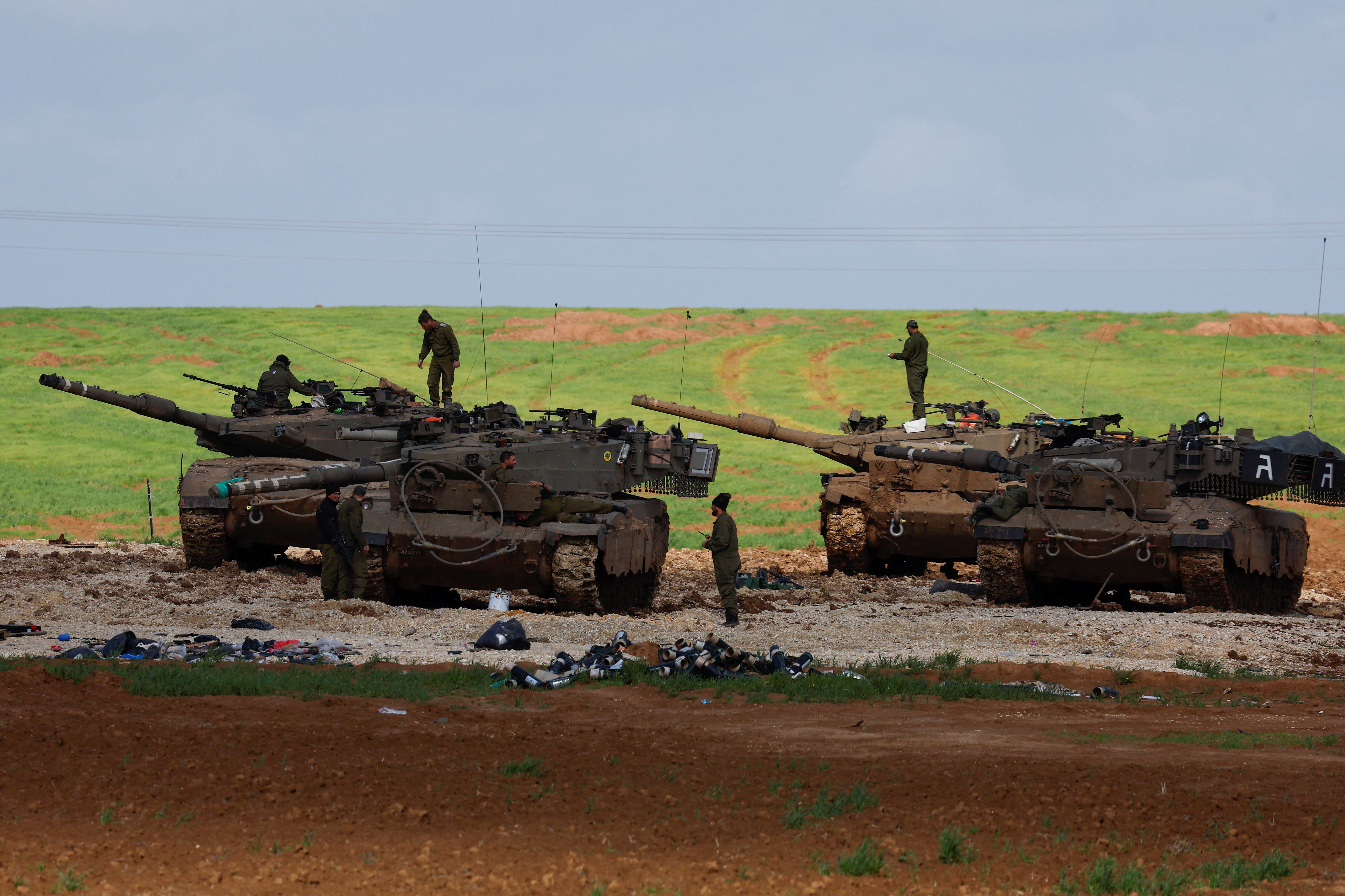 Israeli soldiers work on top of their tanks near the northern Gaza border in Israel, January 30, 2024 [Amir Cohen/Reuters]