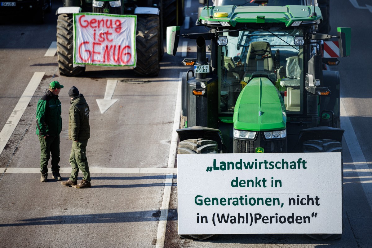 Banners reading 'Enough is enough' (L) and 'Agriculture thinks in generations, not in (legislative) periods' are fixed on tractors during a protest against the federal government