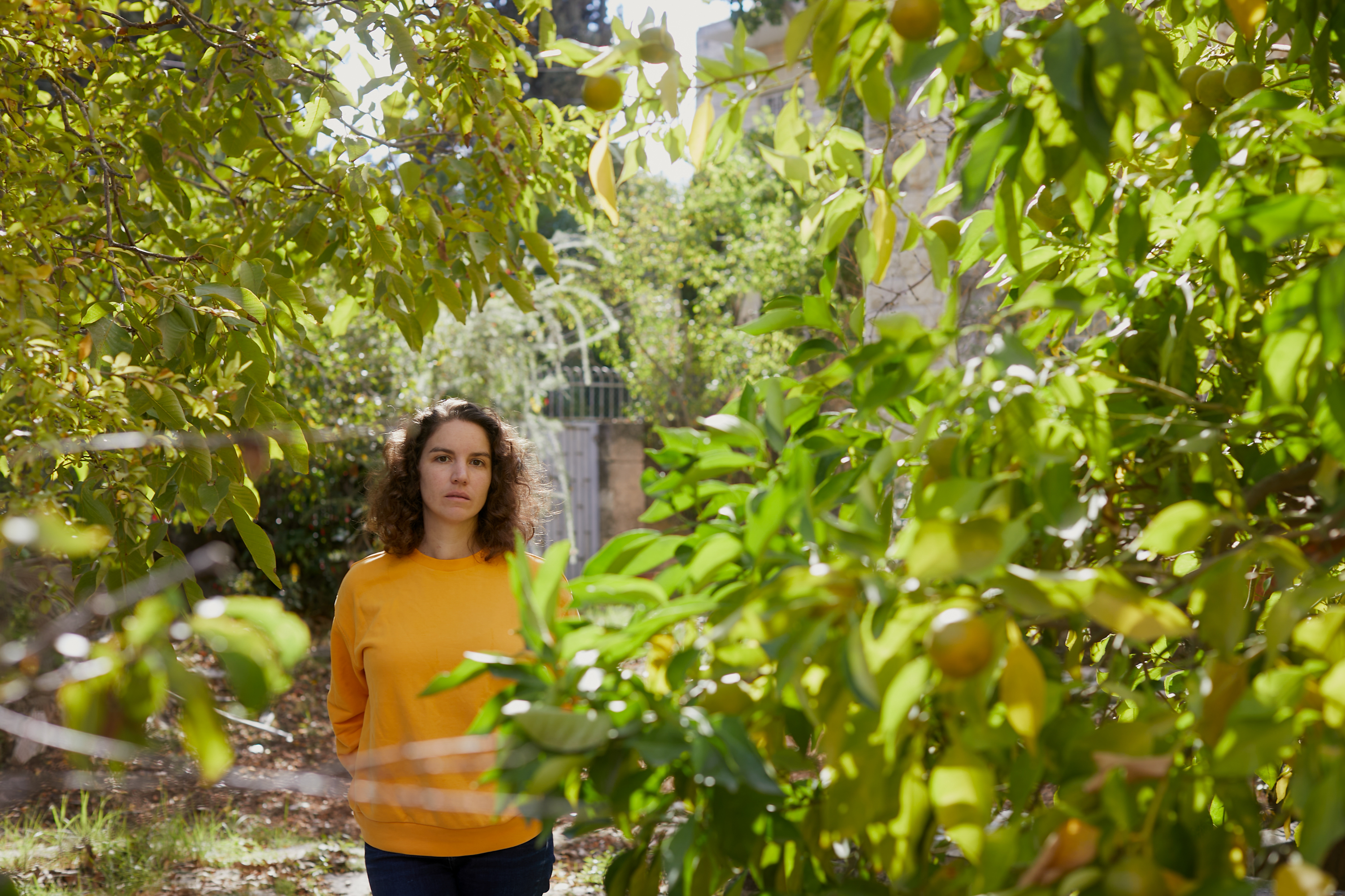 Ines in yellow sweatshirt in an orchard