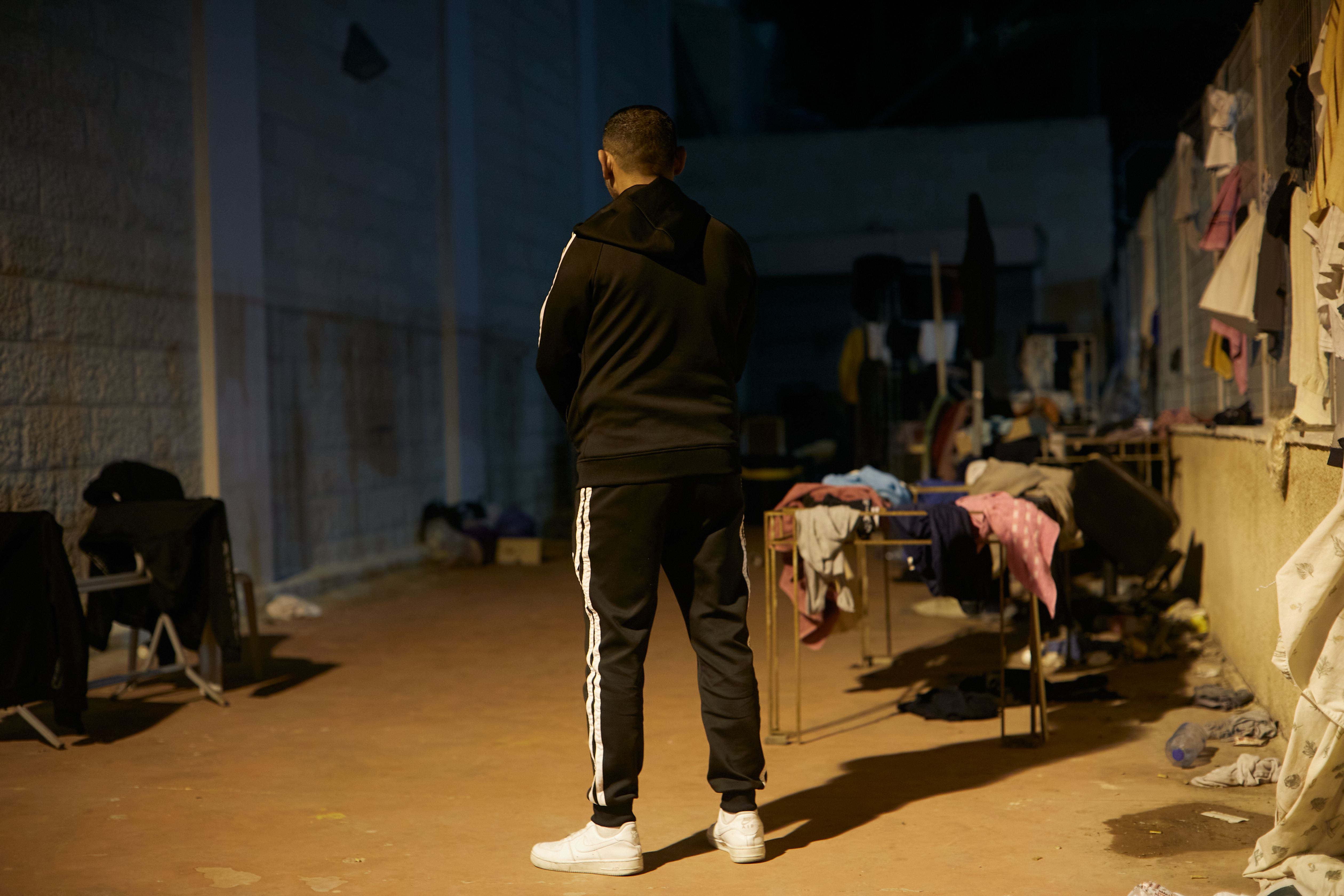 Raed standing with his back to the camera in a dark room