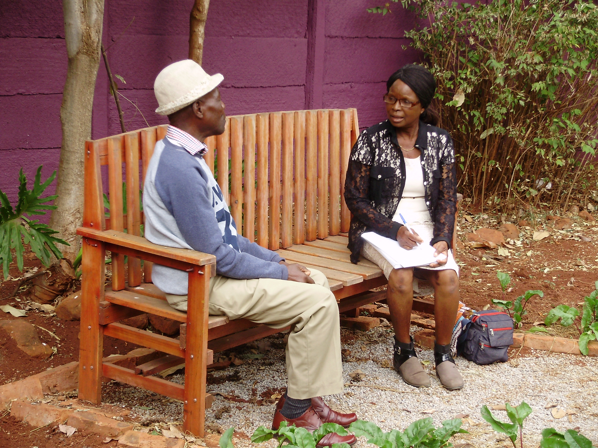 A grandmother sits with a male patient during a Friendship Bench session