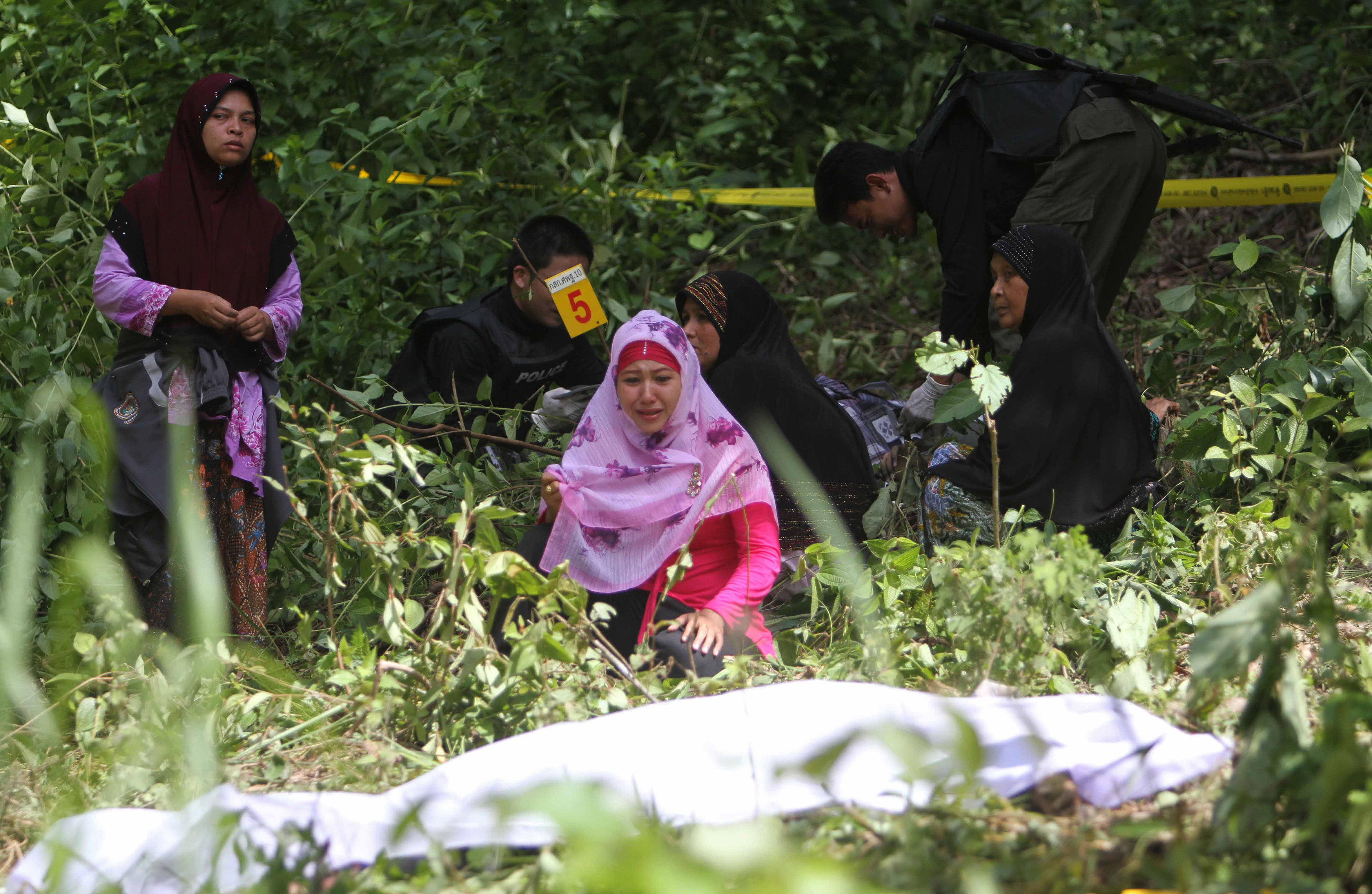 Relatives sit next to the body of a suspected Muslim separatist in southern Thailand’s Yala province