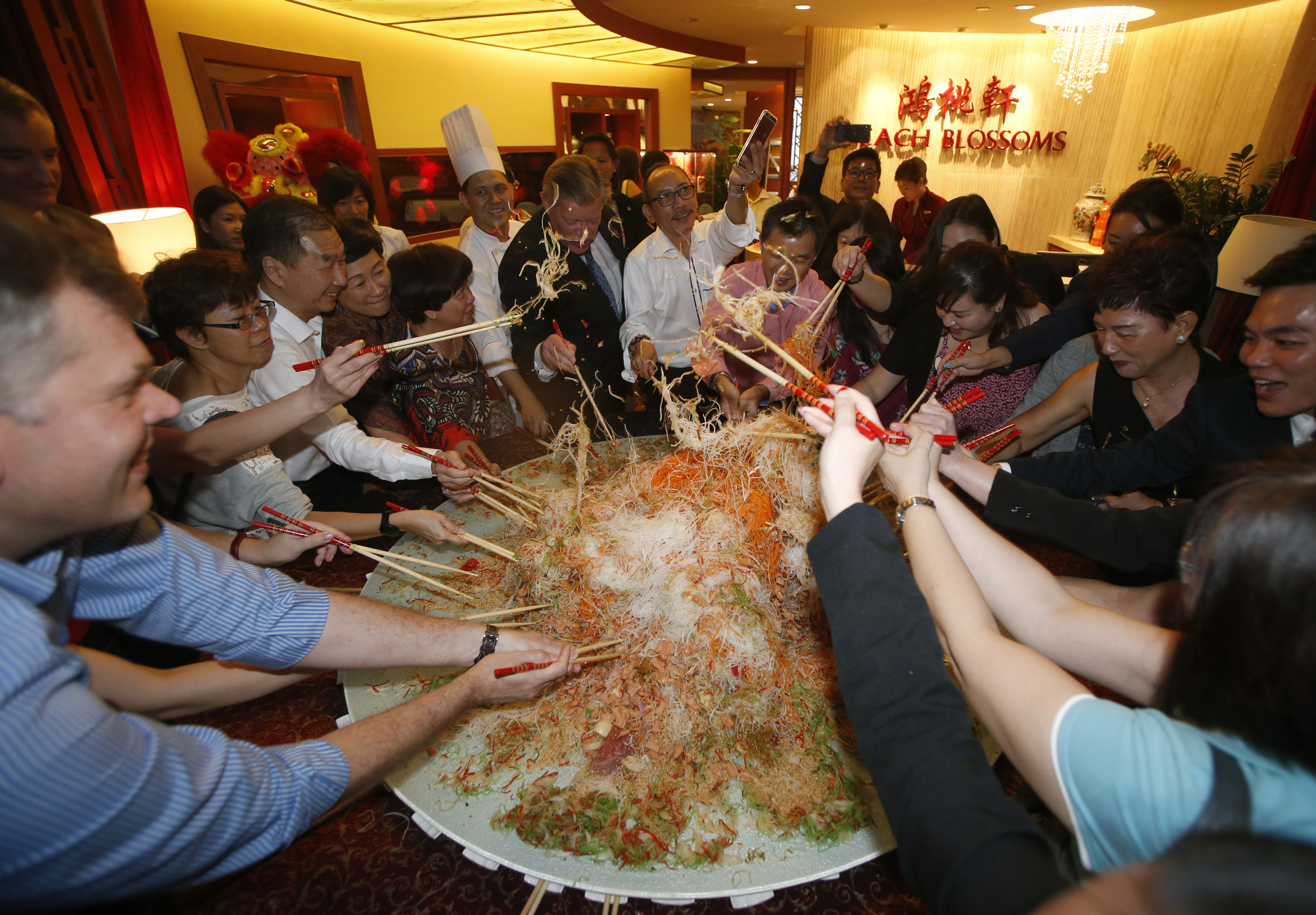 Guests toss an 88 kg plate of yusheng or raw fish during a "lo hei" dinner ahead of the Lunar New Year in Singapore January 8, 2016.