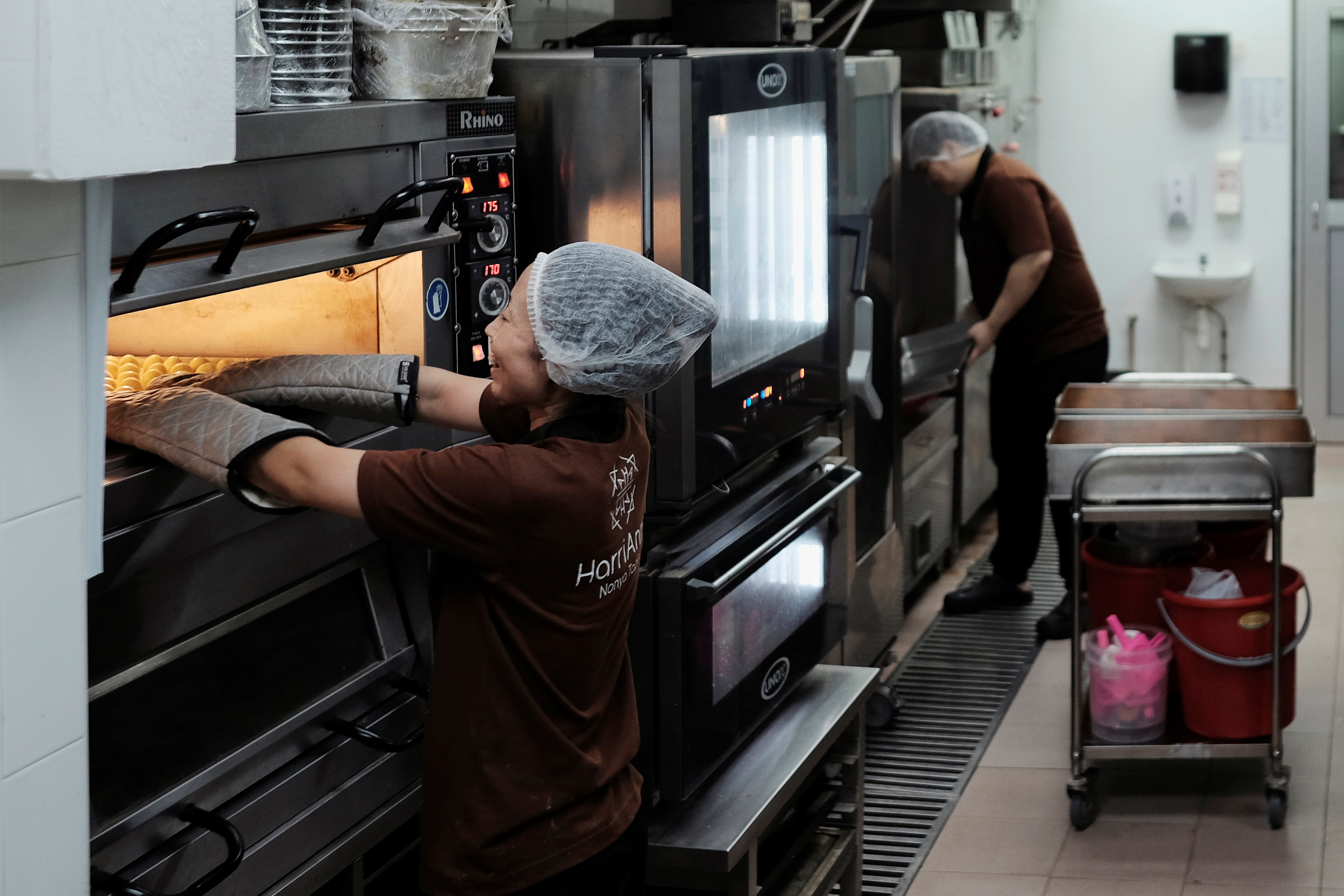 A worker reacts while pulling out a tray of pineapple tarts from an oven in the central kitchen of traditional Peranakan confectionery HarriAnns in Singapore April 20, 2018.