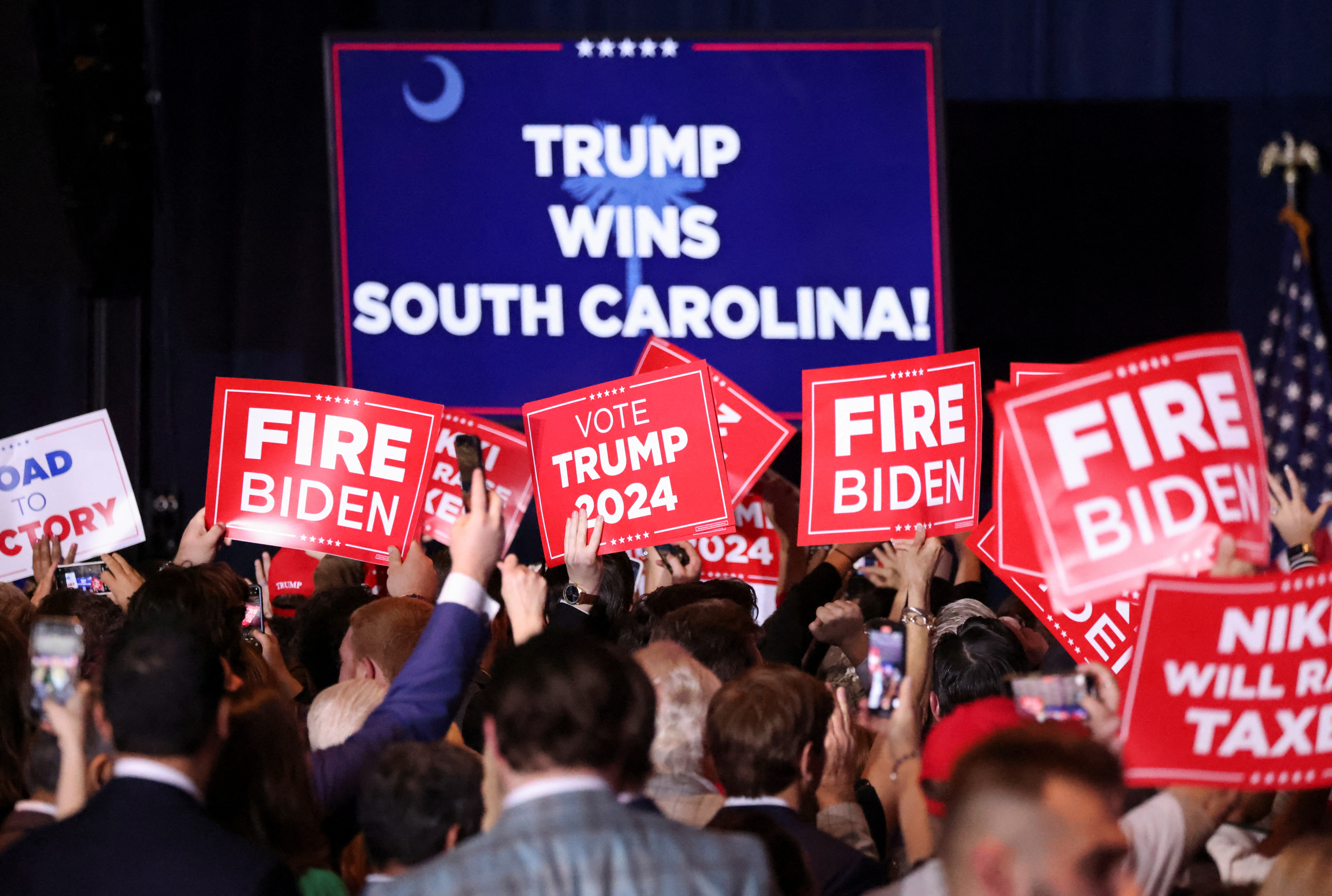 Trump supporters hold signs as they attend his primary night party in Columbia, South Carolina, on February 24