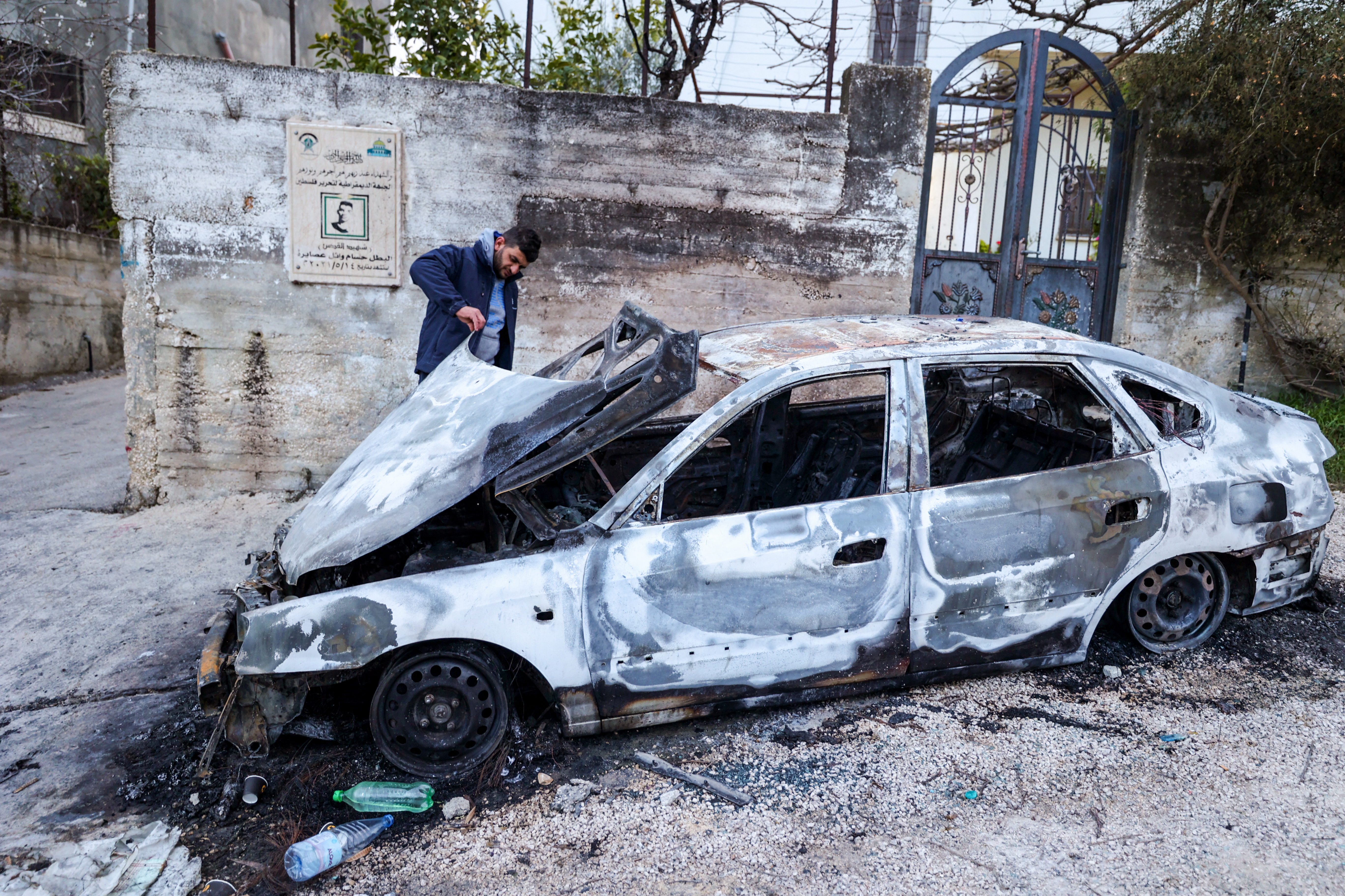 A Palestinian man inspects a car damaged during a reported attack by Israeli settlers in the village of Asira al-Qibliyah, south of Nablus [AFP]