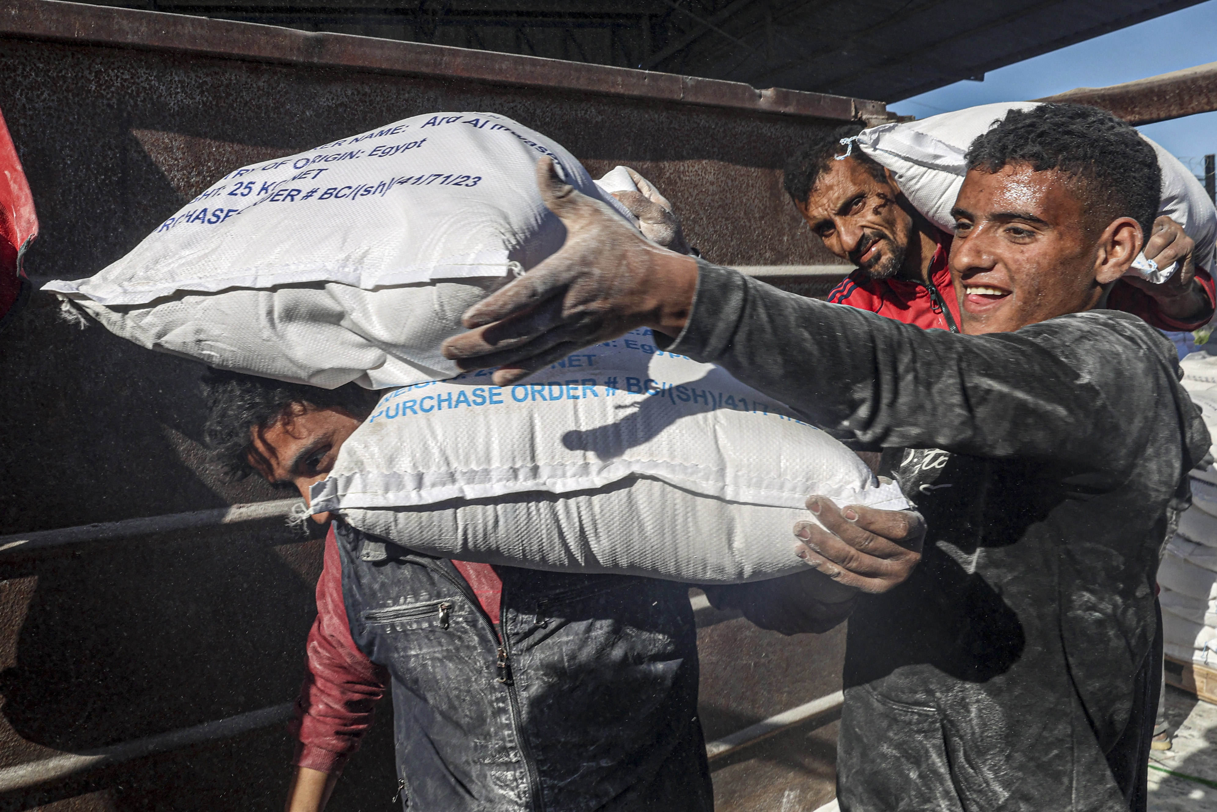Workers unload bags of humanitarian aid that entered Gaza by truck through the Kerem Shalom (Karem Abu Salem) border crossing in the southern part of the Palestinian territory on February 17