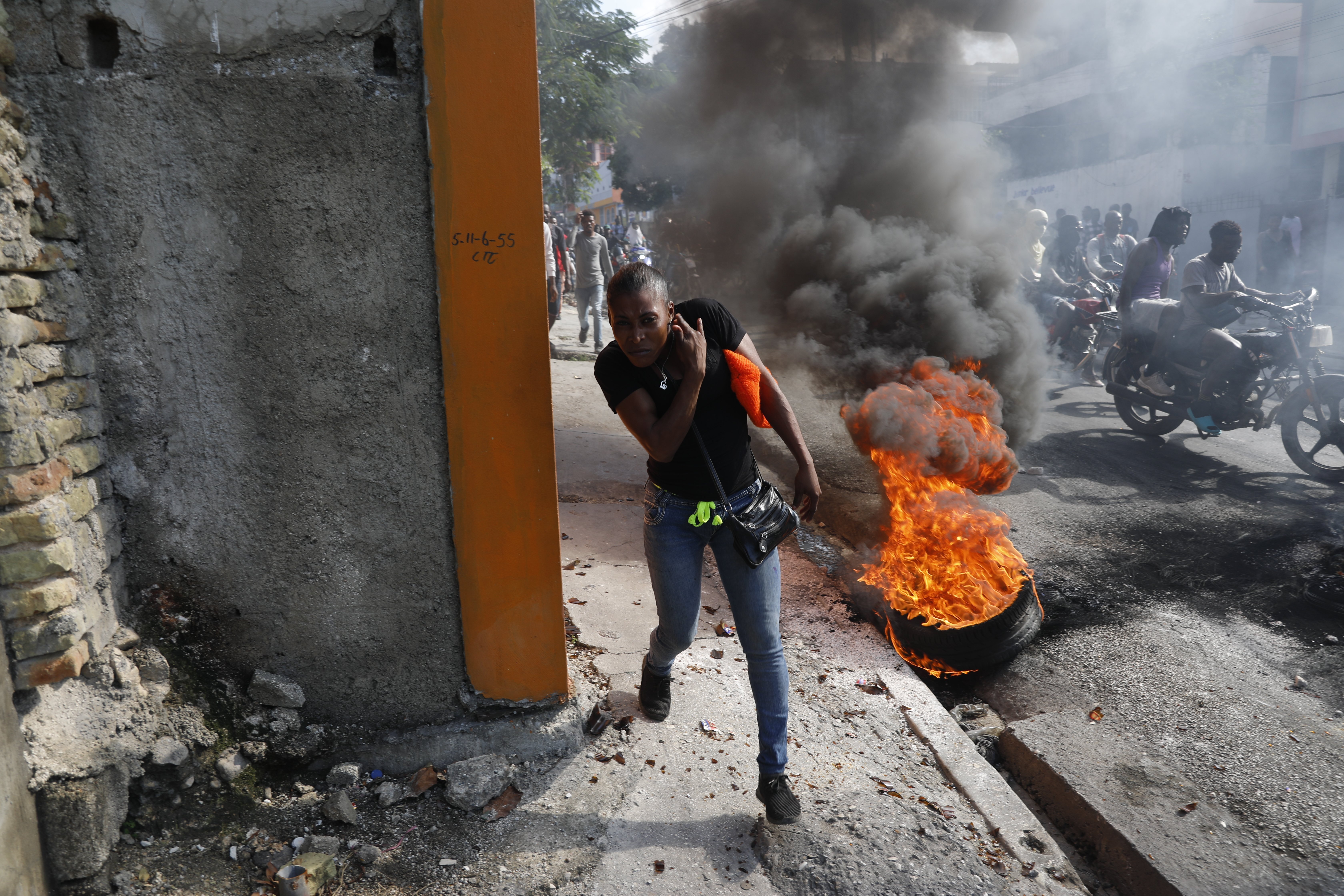 A person runs past burning tires