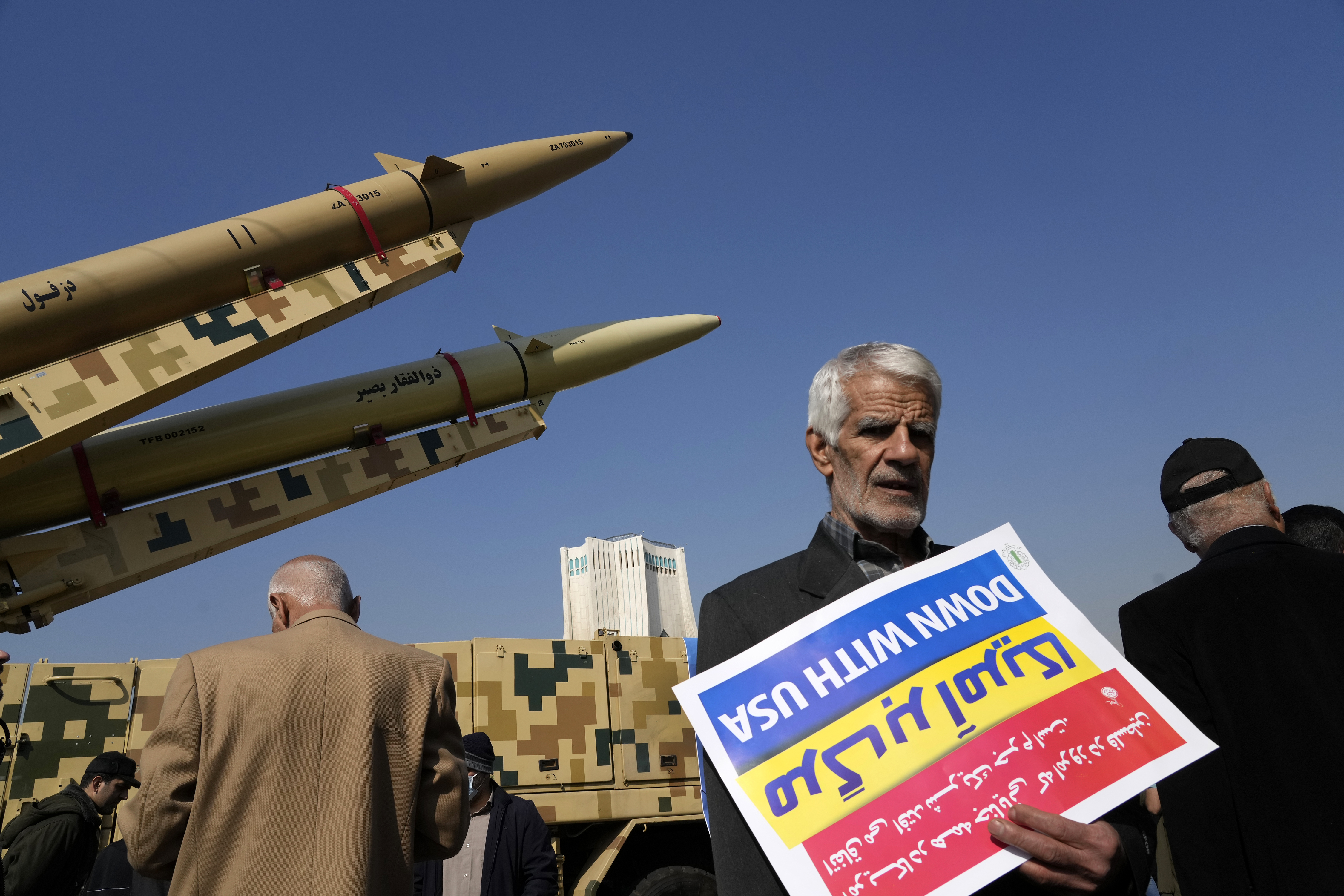 A man carries an anti-US placard upside down in front of the Iranian-made missiles displayed in the annual rally commemorating Iran’s 1979 Islamic Revolution in Tehran, February 11, 2024