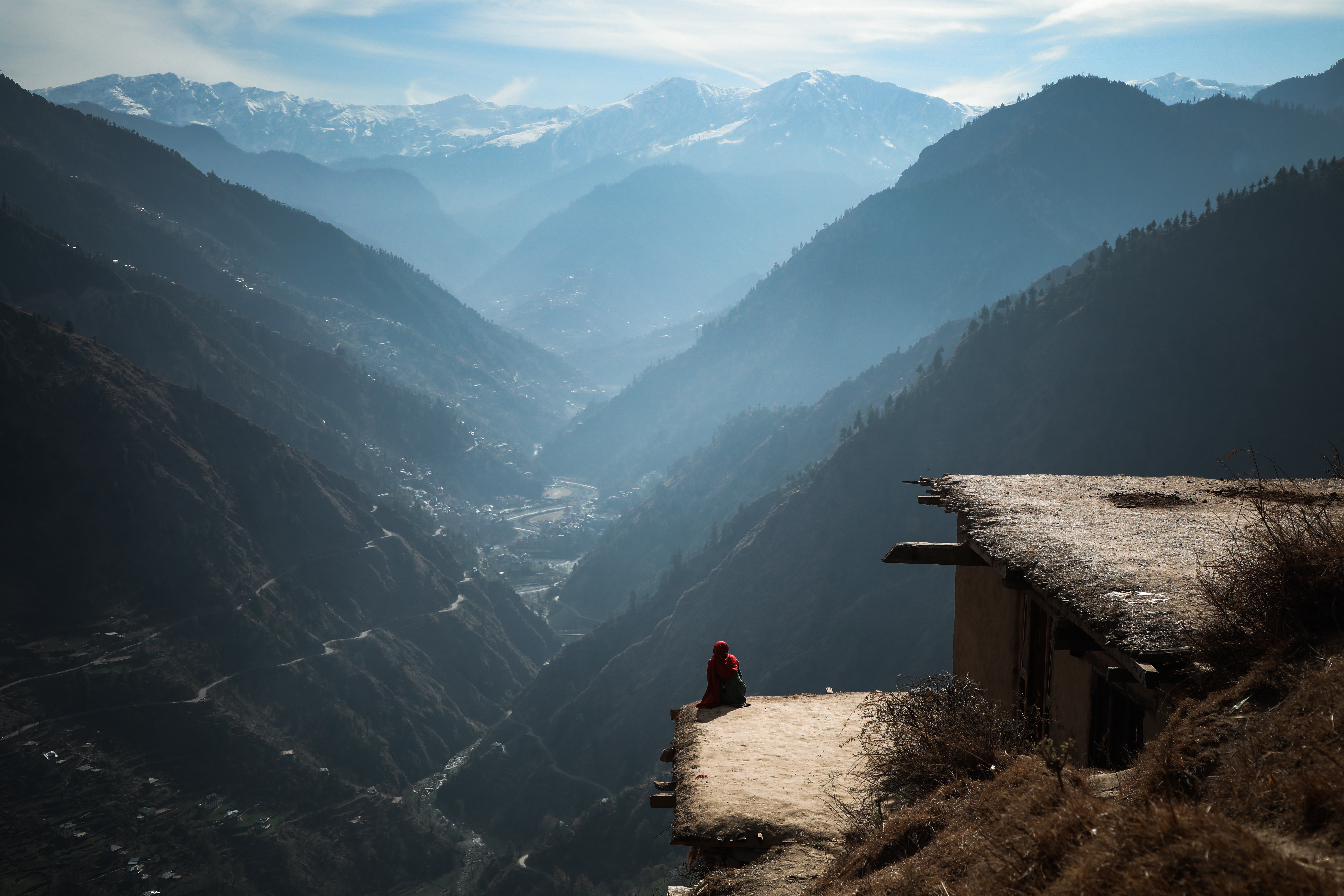 A young woman sits outside her house, constructed from mud, after finishing her chores in the village of Dadkhai