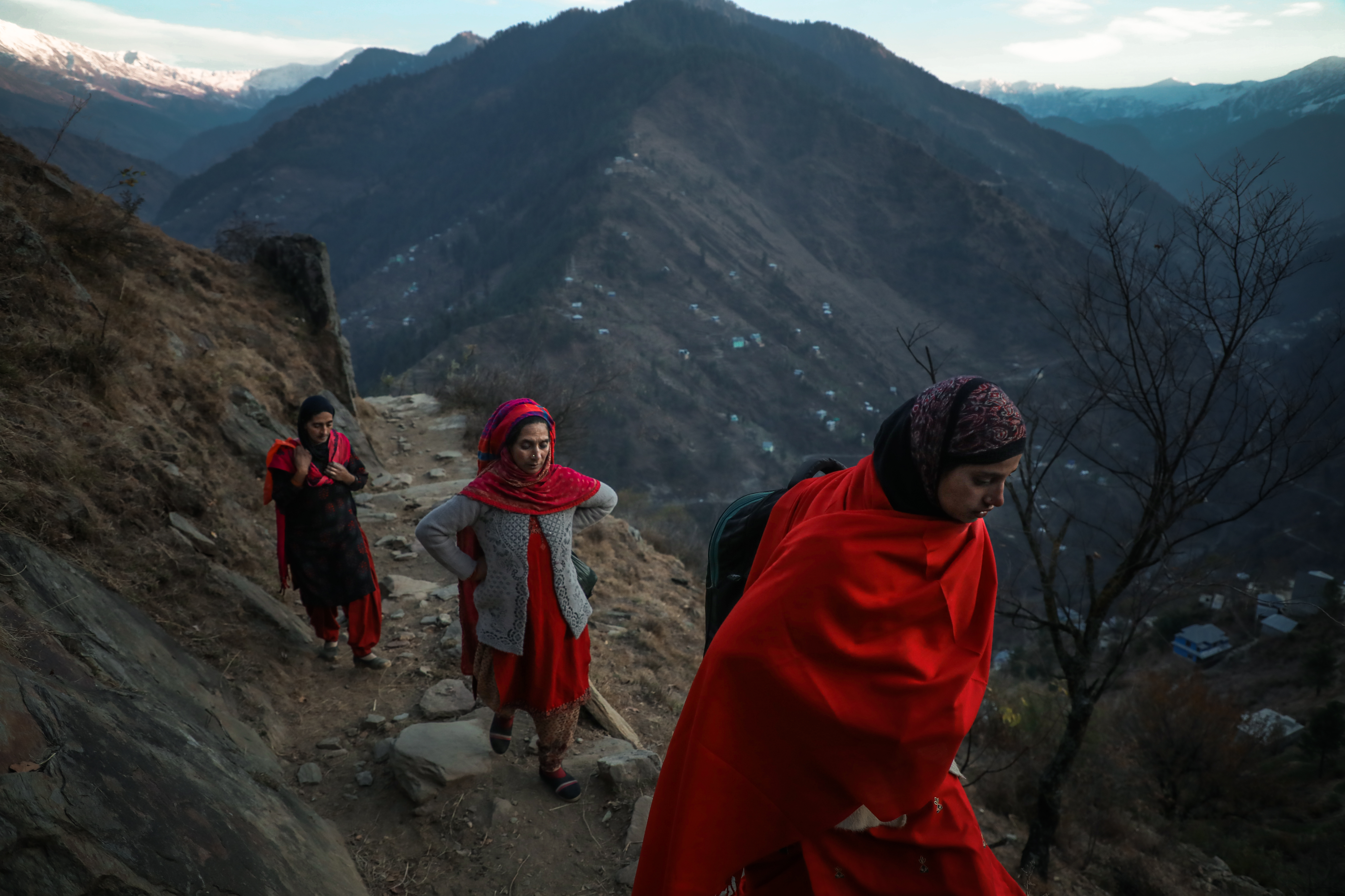 Local women from Dadkhai village carry daily essentials on their shoulders as they climb the mountain, making their way home