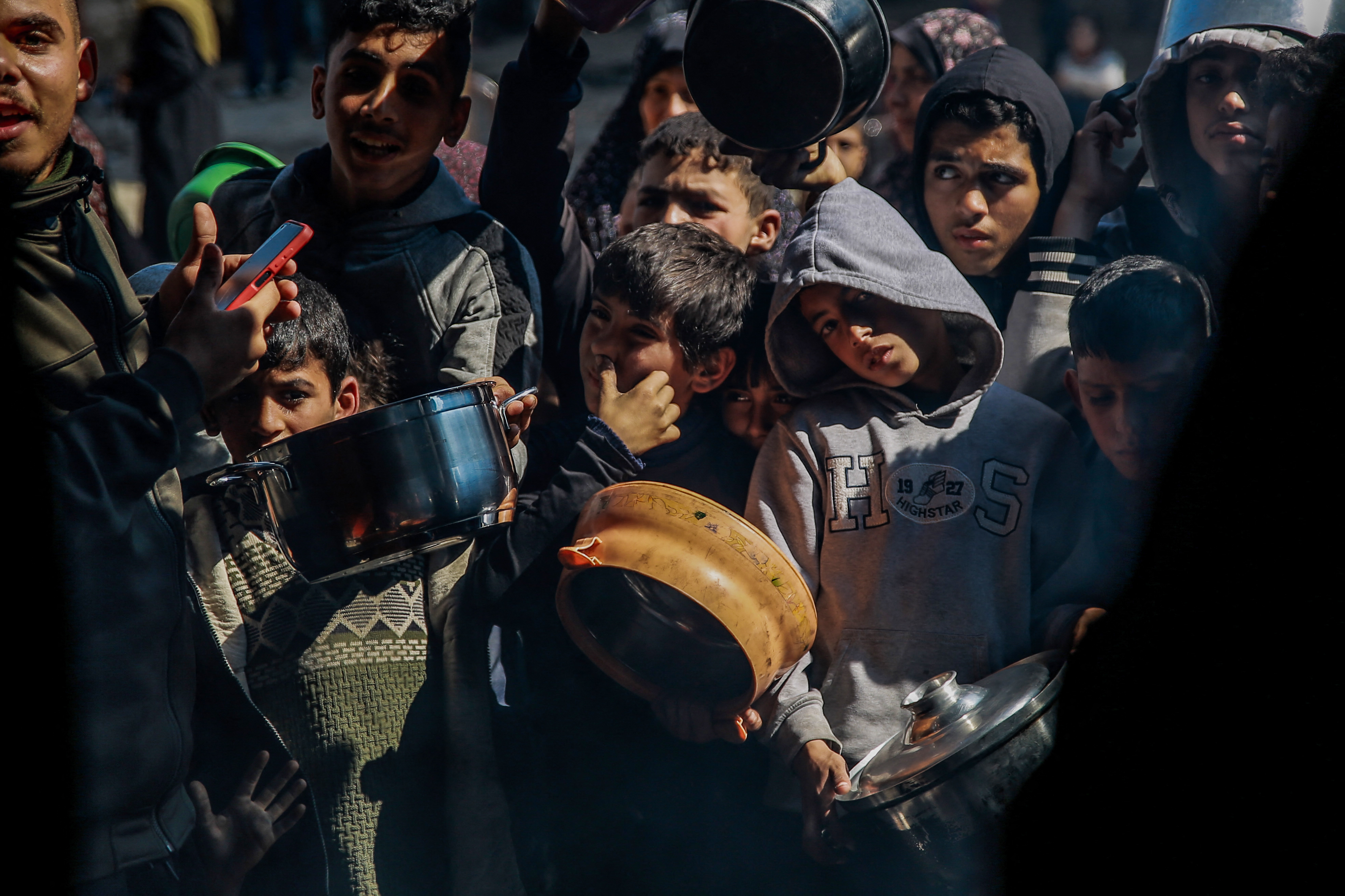 Palestinian children wait to get food from an aid distribution team in Beit Lahiya in northern Gaza on February 26, 2024 [AFP]