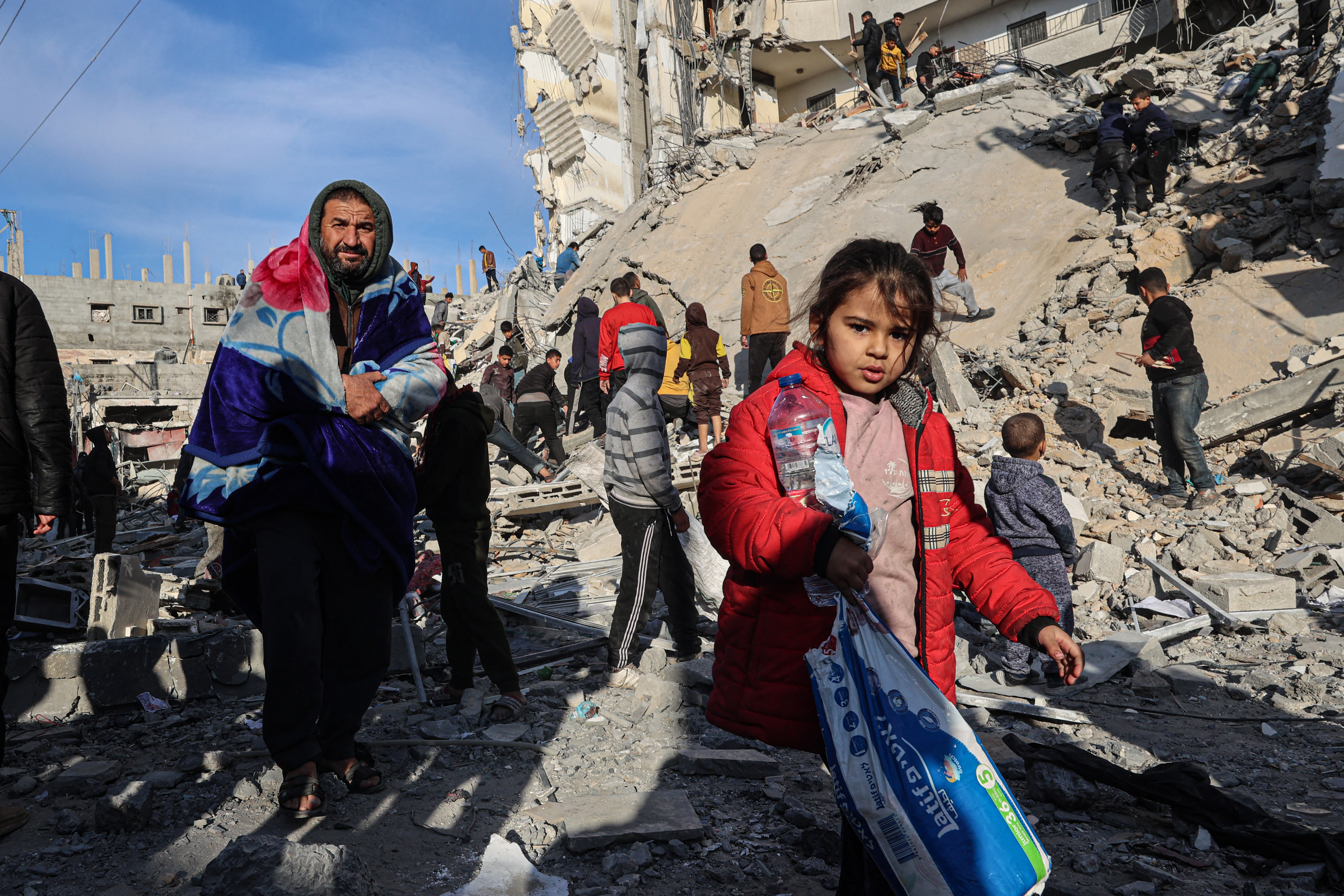 Palestinians walk away with some items salvaged from the rubble of a residential building hit in an overnight Israeli air strike in Rafah in the southern Gaza Strip on March 9