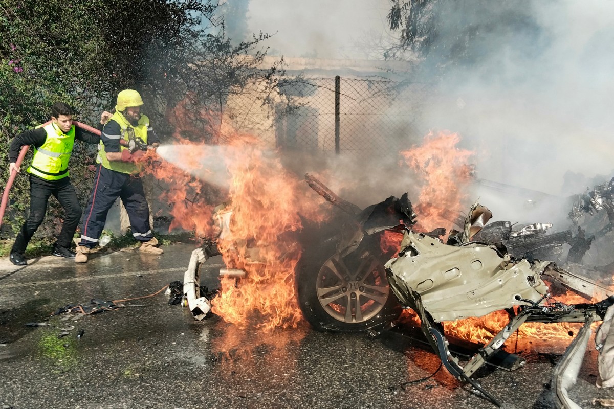 Firefighters douse a burning car hit in a reported Israeli drone attack in Tyre, Lebanon, on March 13, 2024 [AFP]