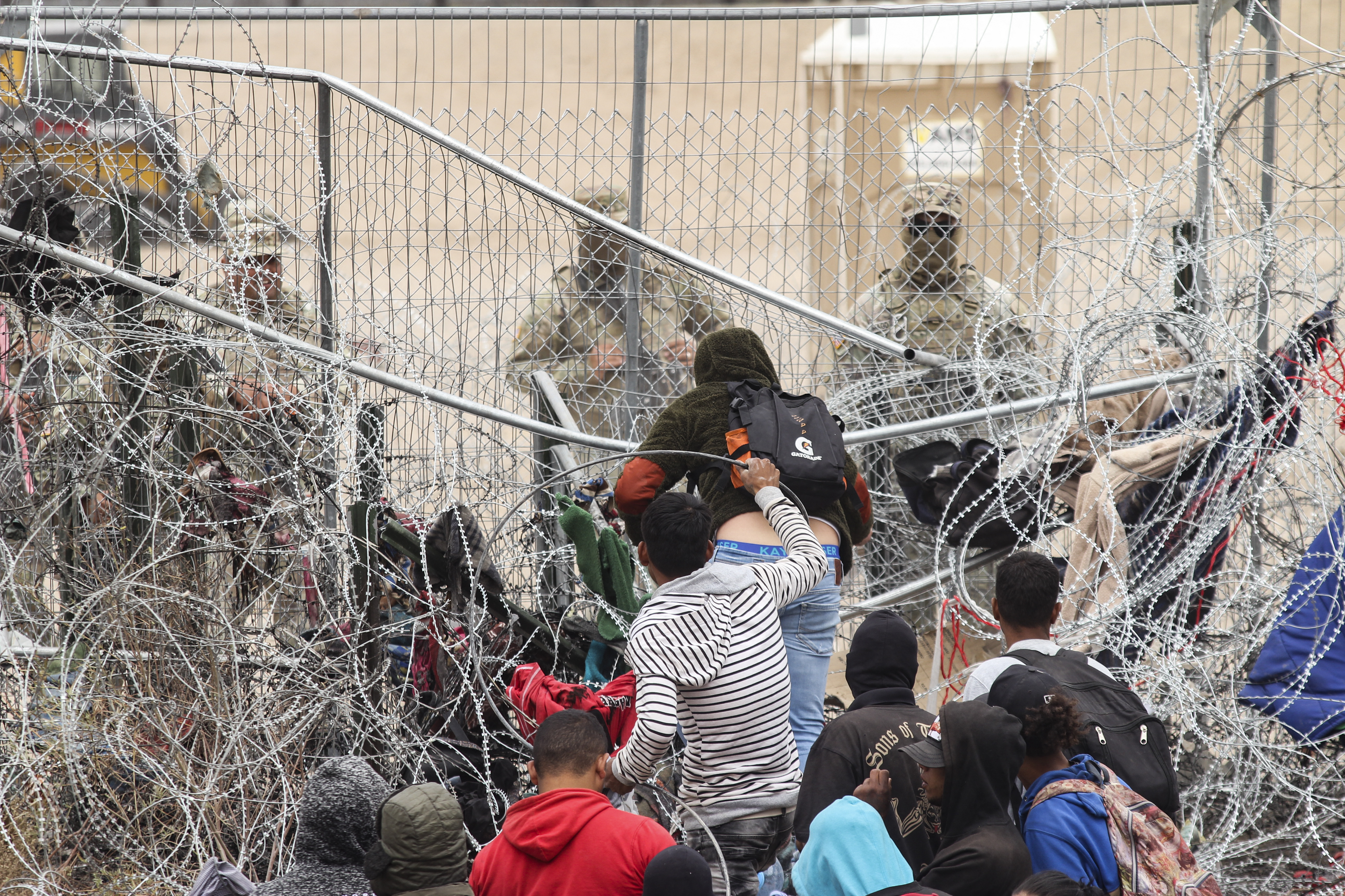 A group of migrant people try to cross a barbed wire fence to reach the US side, as seen from Ciudad Juarez, Mexico on March 20, 2024.