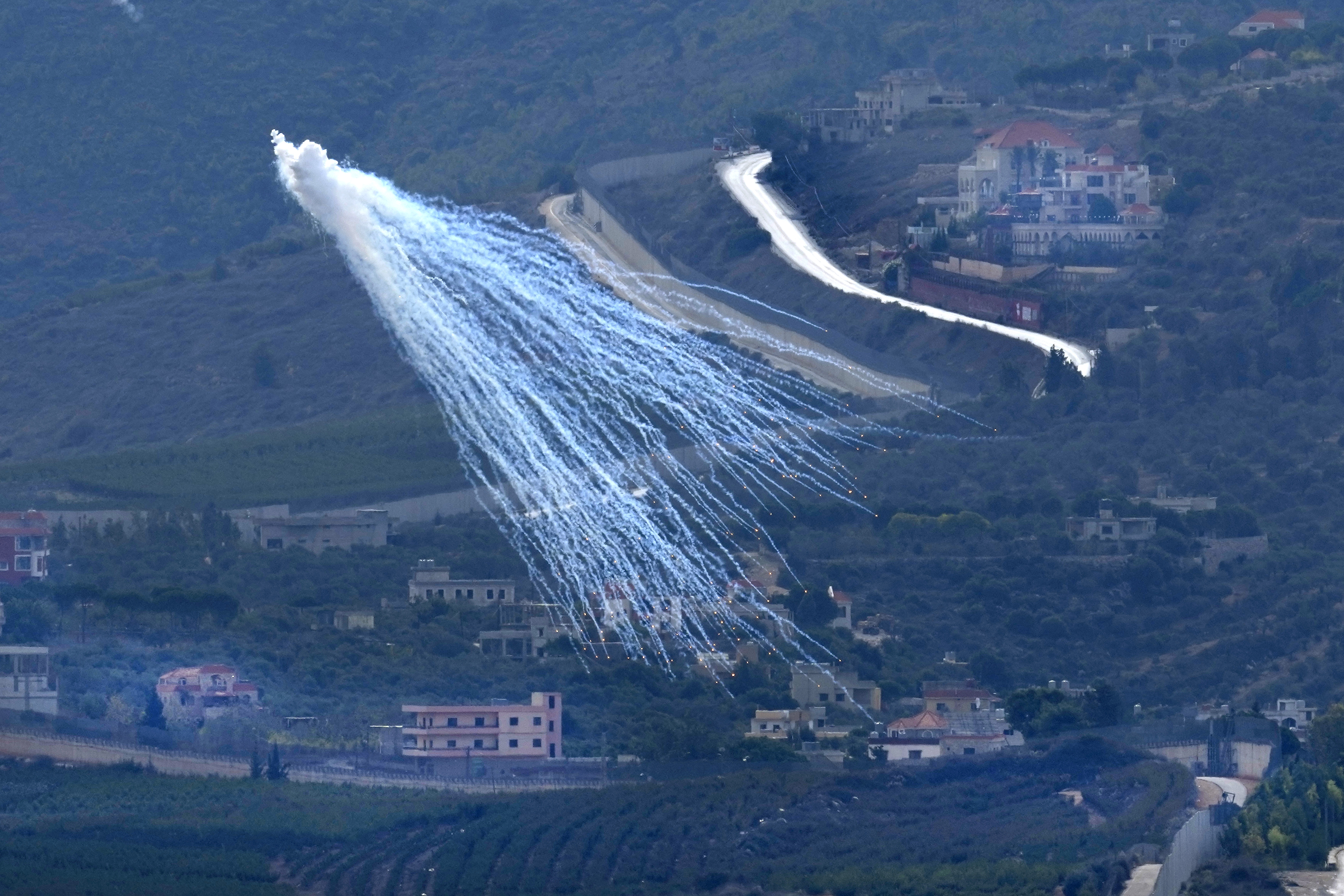 A shell that appears to be white phosphorus from Israeli artillery explodes over Kfar Kila