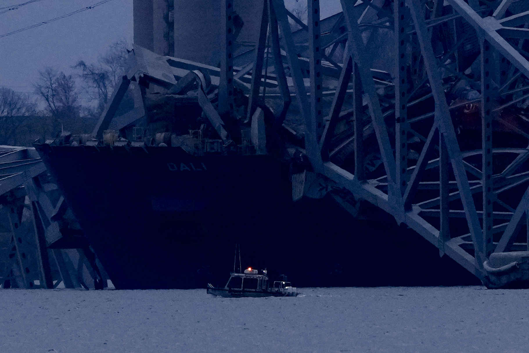 A container ship rests against wreckage of the Francis Scott Key Bridge as night falls on Tuesday