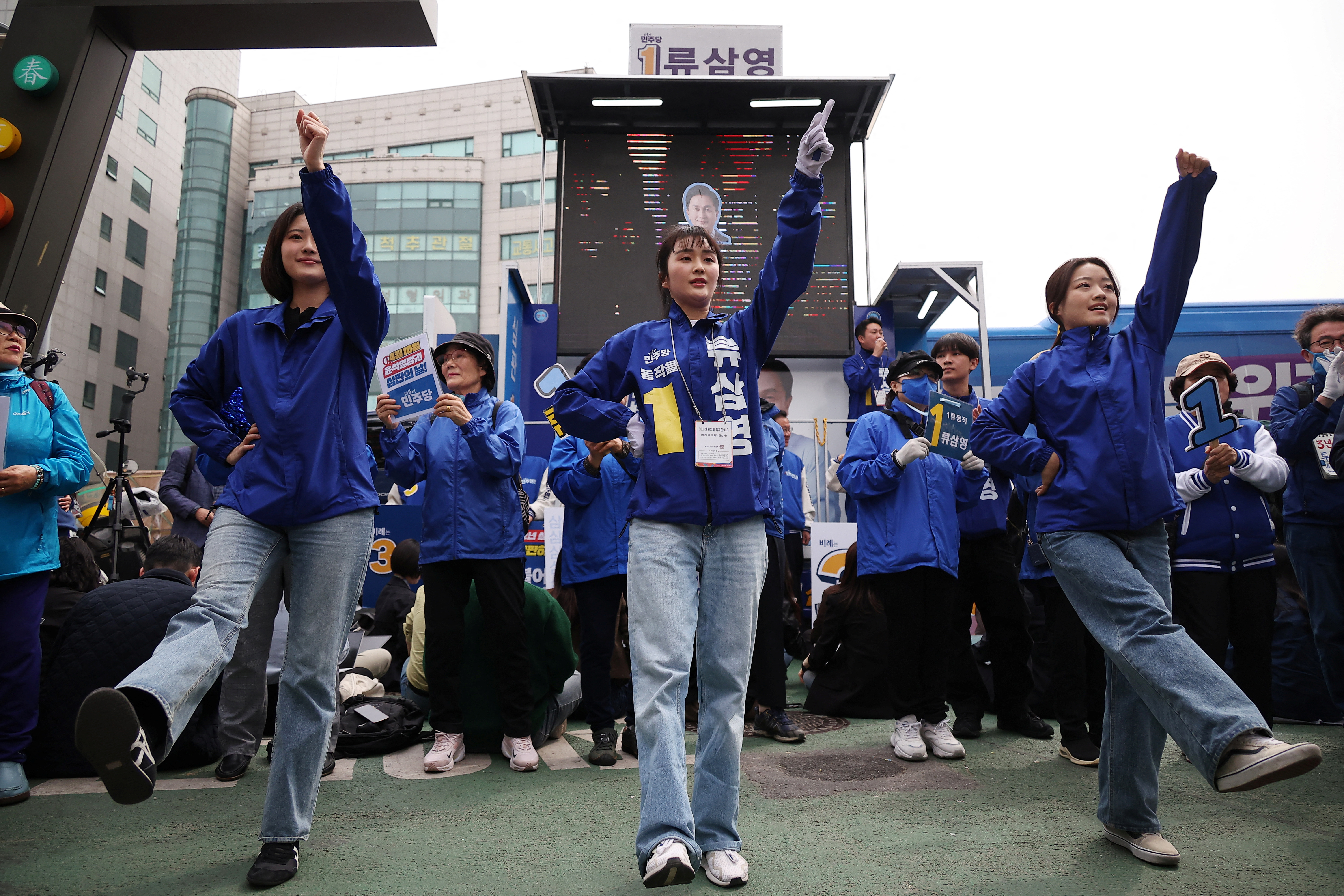 Election campaigners for the main opposition Democratic Party perform a dance routine at a campaign rally, They are dressed in the party's colours of blue and white. 