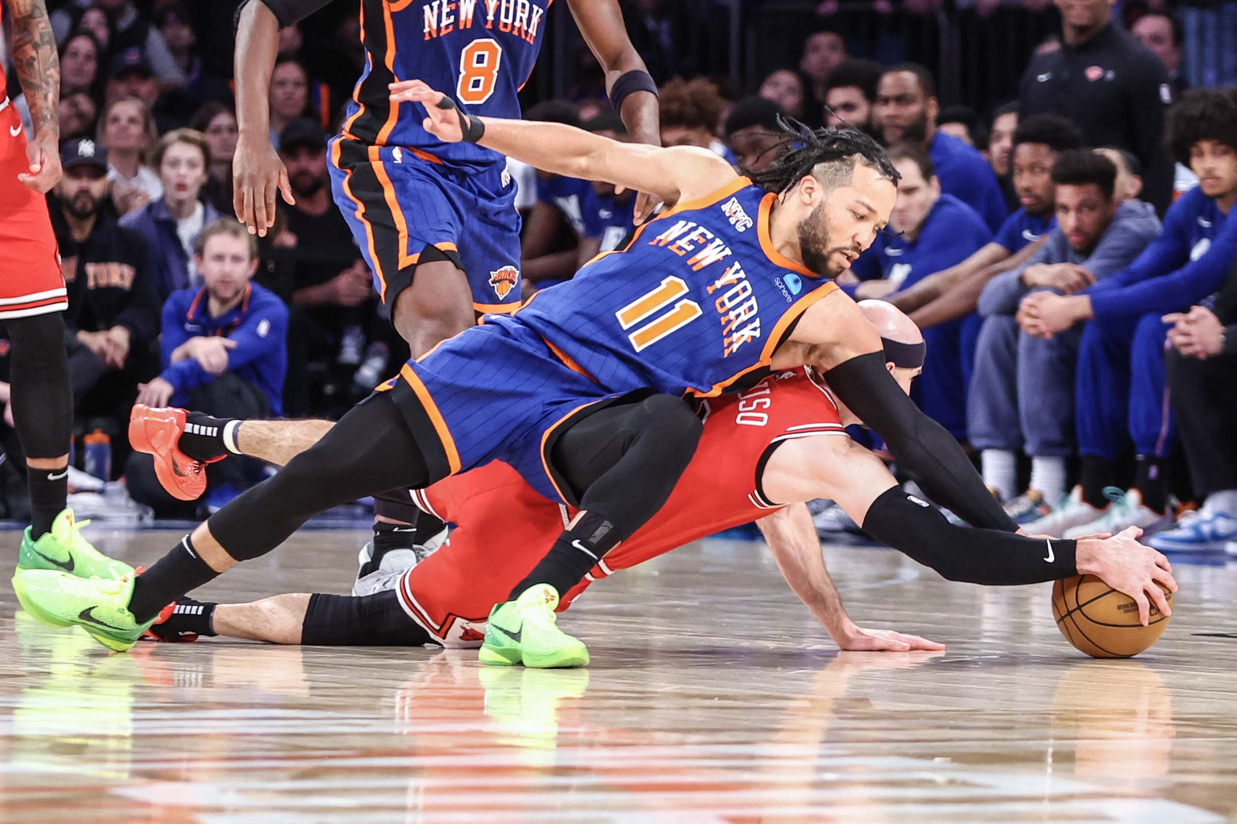New York Knicks guard Jalen Brunson, 11, and Chicago Bulls guard Alex Caruso, 6, fight for a loose ball in overtime at Madison Square Garden on April 14, 2024, in New York
