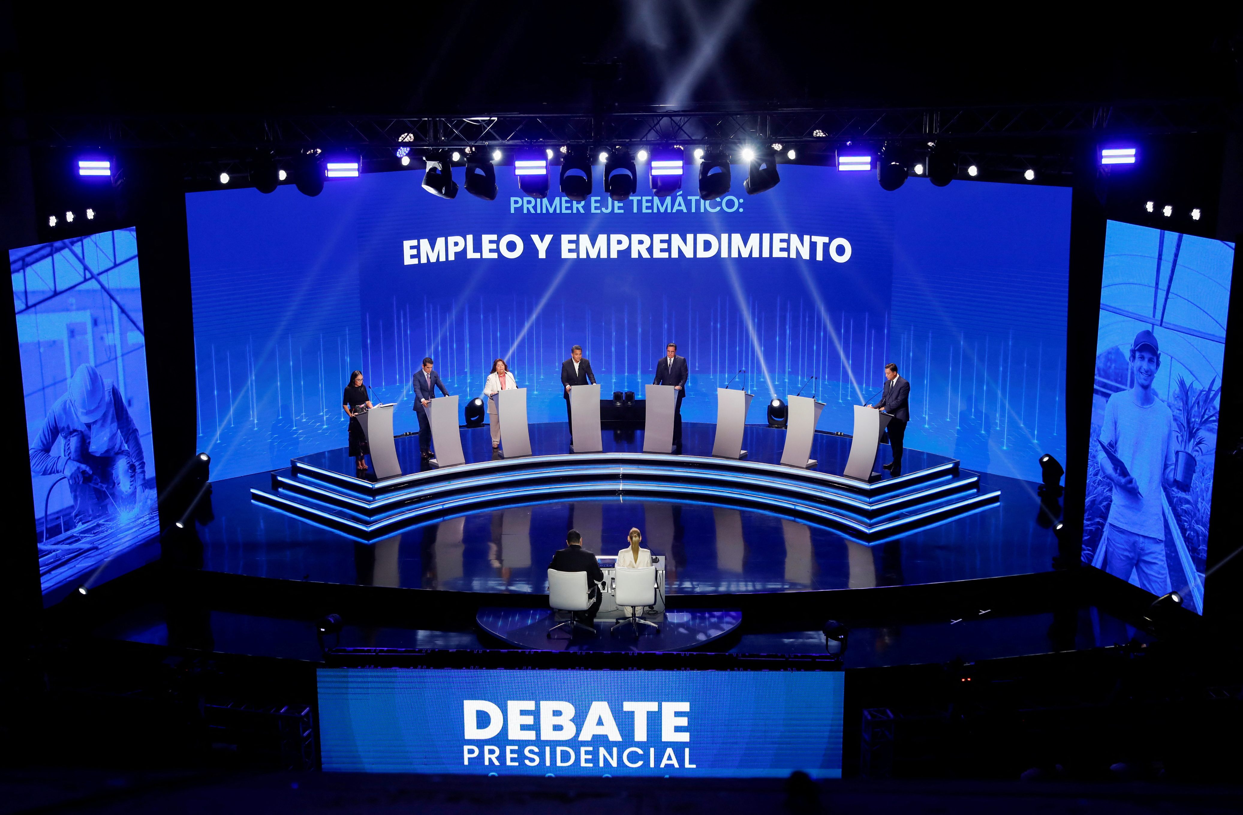 A view of a debate stage in Panama, where eight candidates prepare to discuss policy from behind silver podiums.