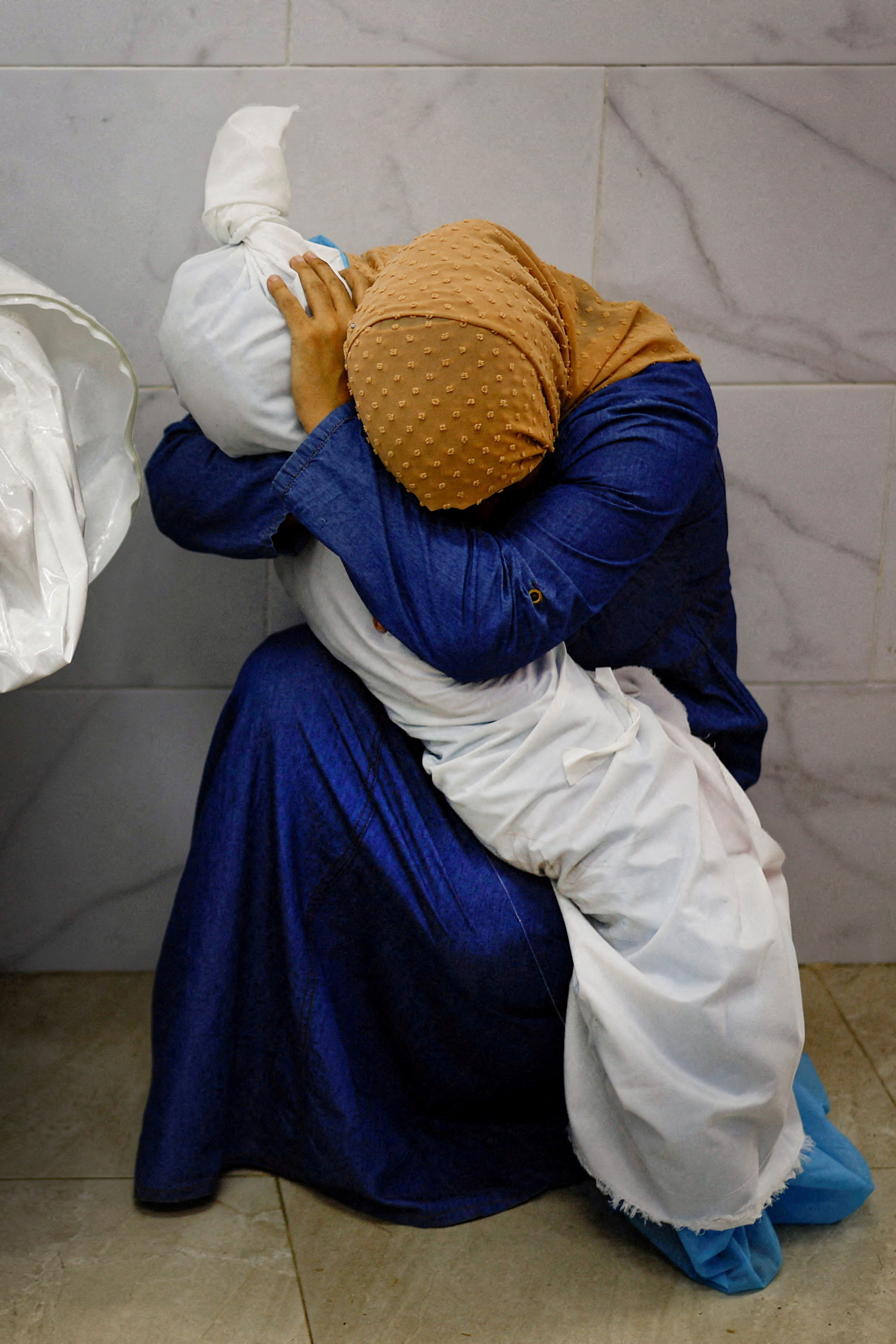 Palestinian woman Inas Abu Maamar, 36, embraces the body of her 5-year-old niece Saly