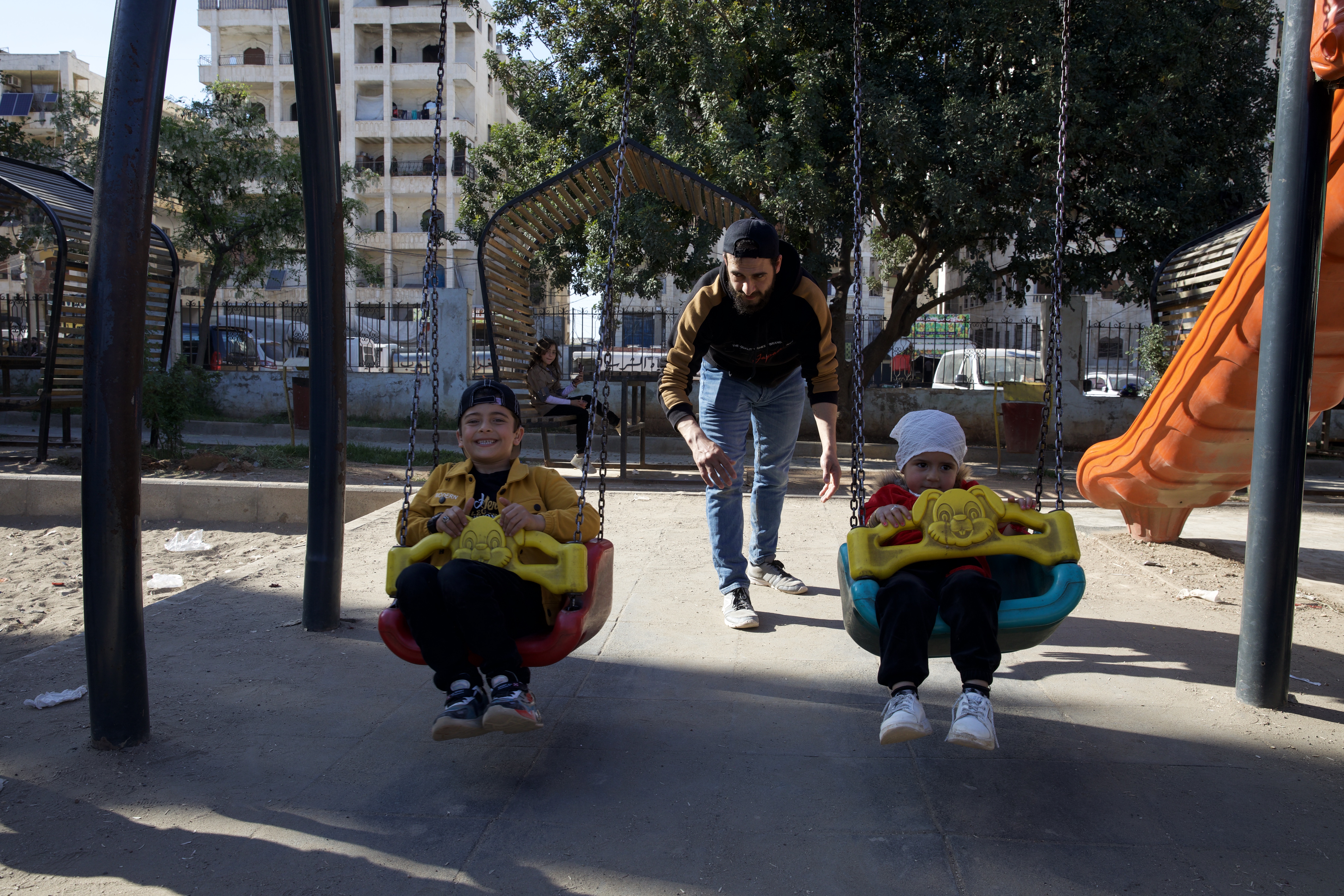 Khalid pushes an excited Aslan and Celine on the park swings