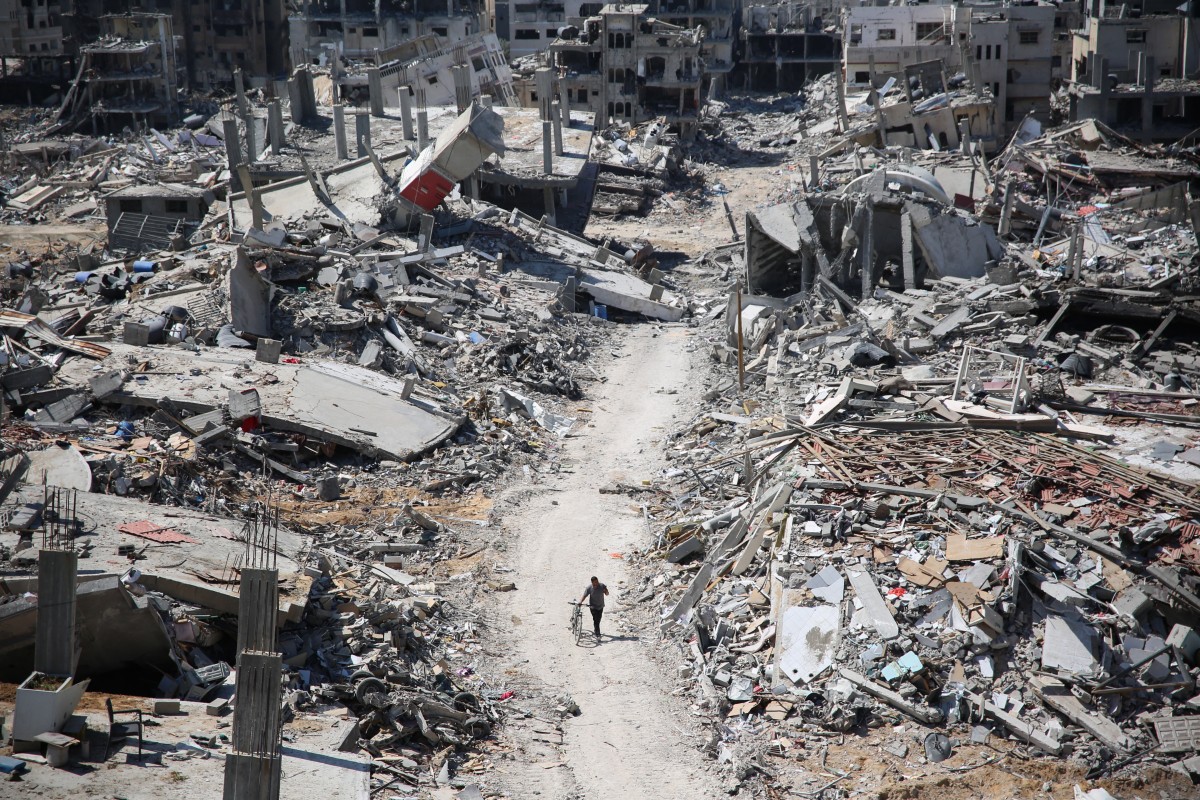 A man pushes a bycicle along as he walks amid building rubble in the devastated area around Gaza's Al-Shifa hospital