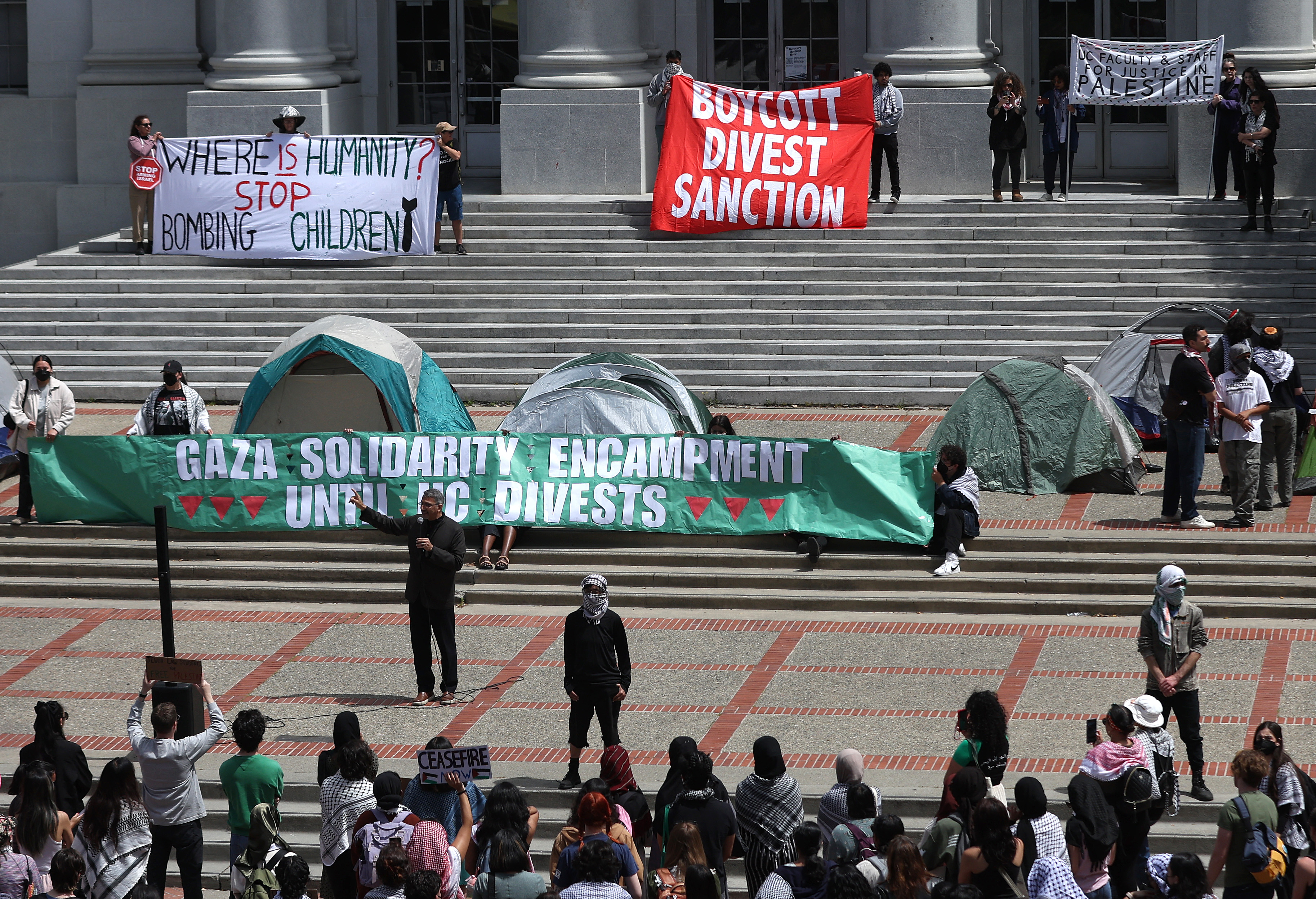 students hold a banner that says UC Berkley divest