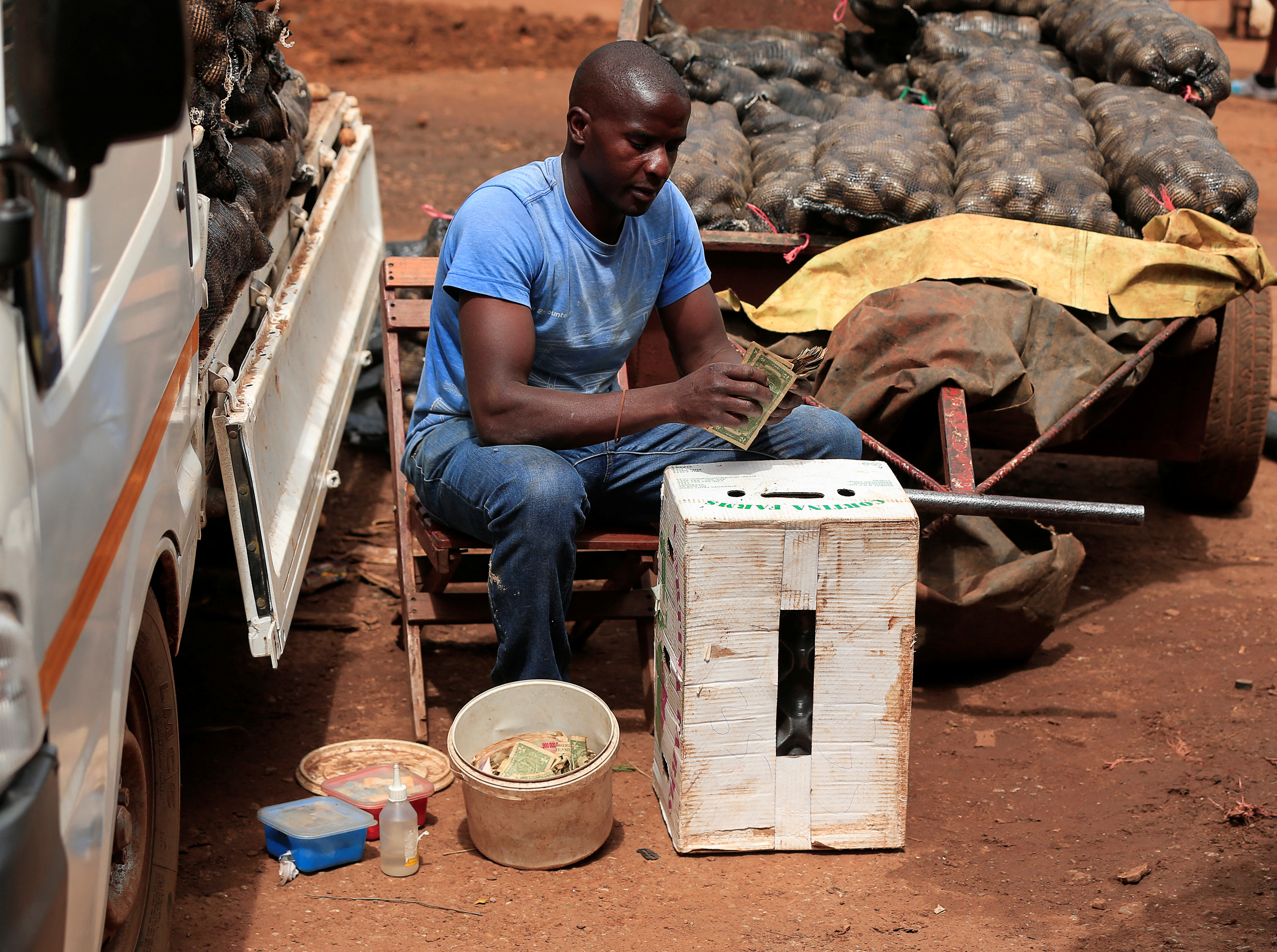 A street money trader repairs damaged banknotes outside a shopping centre in Harare
