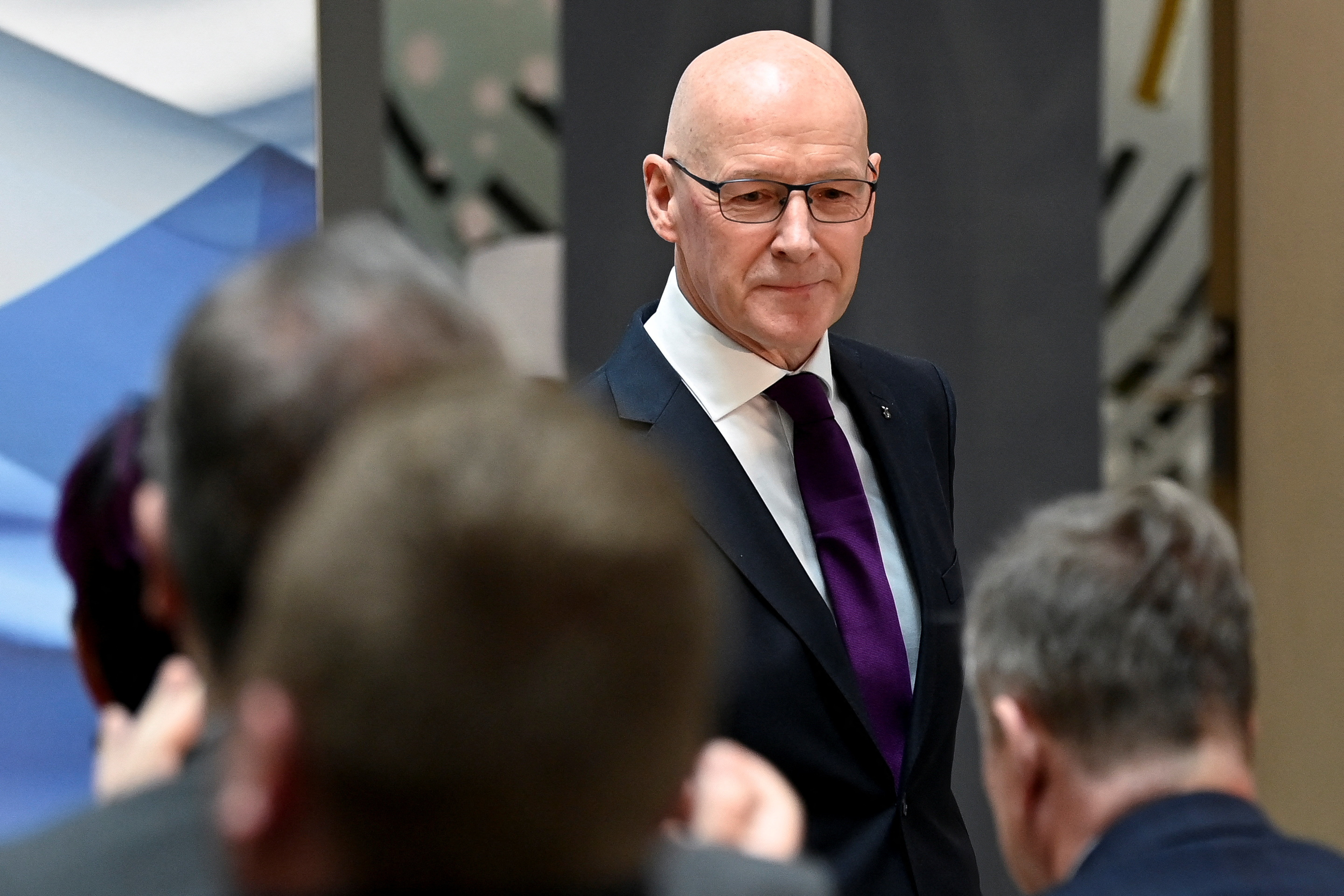 a man in a quite and tie wearing glasses
