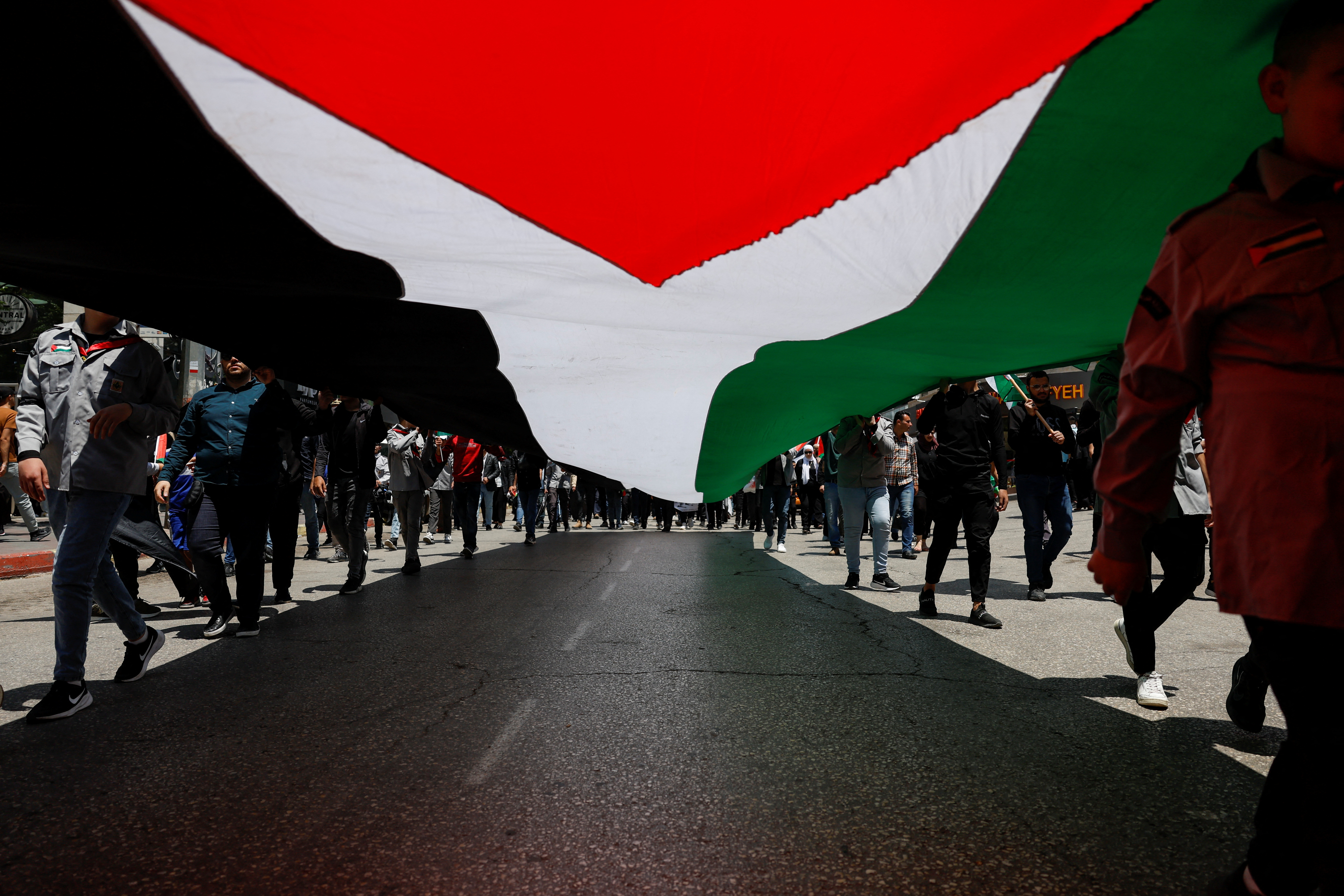 Palestinians hold a Palestinian flag as they take part in a protest to mark the 76th anniversary of the Nakba, the "catastrophe" of their mass dispossession in the 1948 war surrounding Israel's creation, in Ramallah