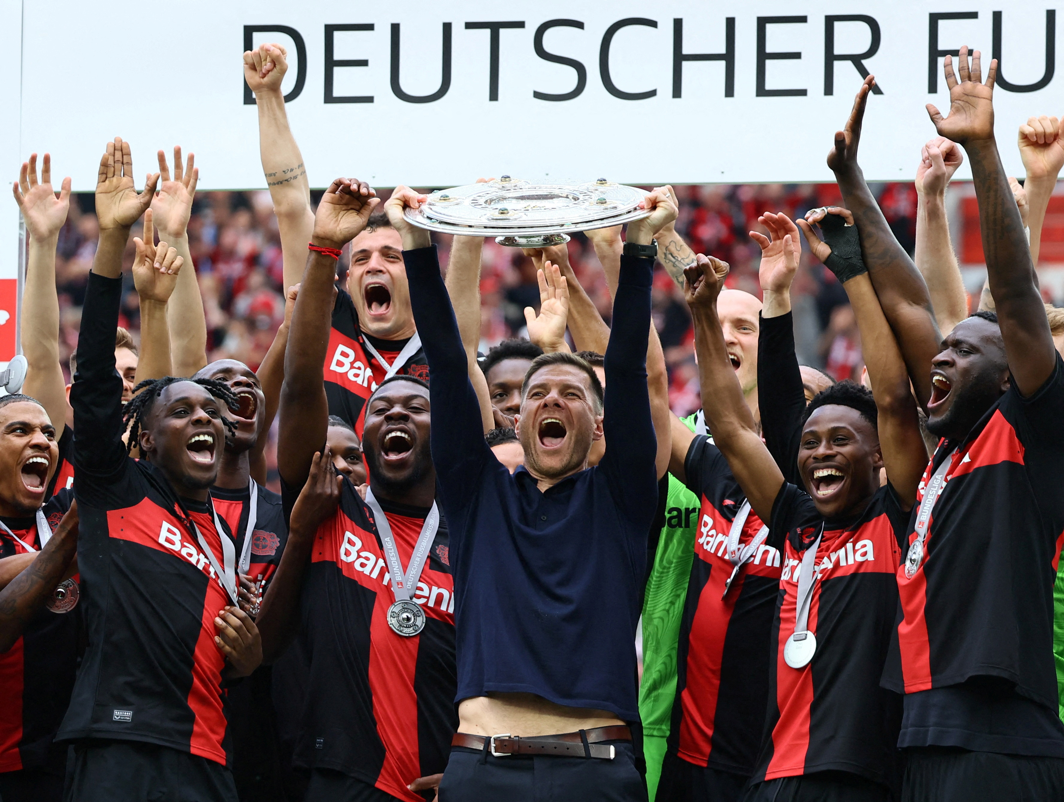 Bayer Leverkusen coach Xabi Alonso celebrates with the trophy and the players after winning the Bundesliga and going unbeaten for the 2023-24 season