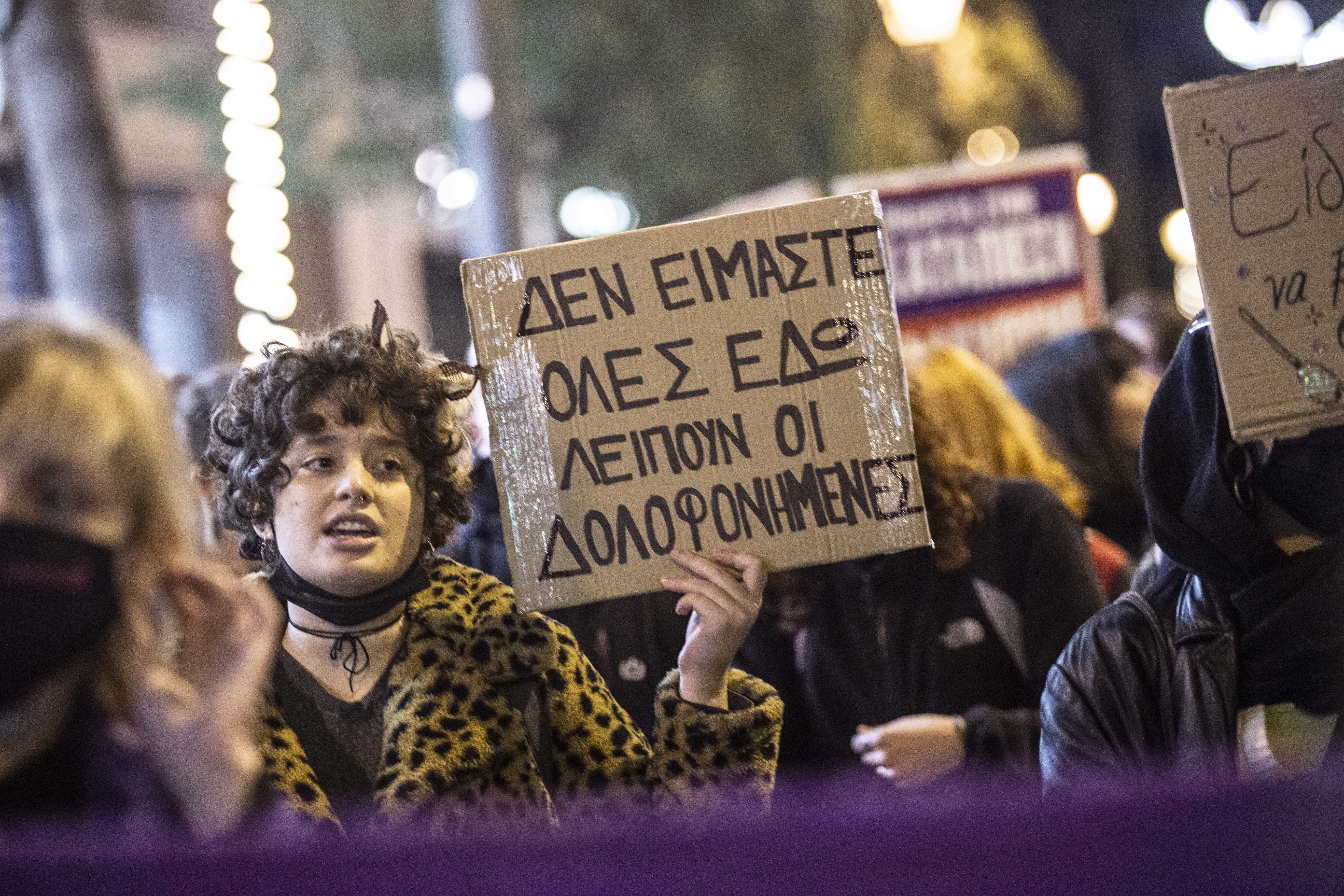 A woman holds a sign saying ‘We are not all here, the murdered are missing’ during protests against femicides in Athens