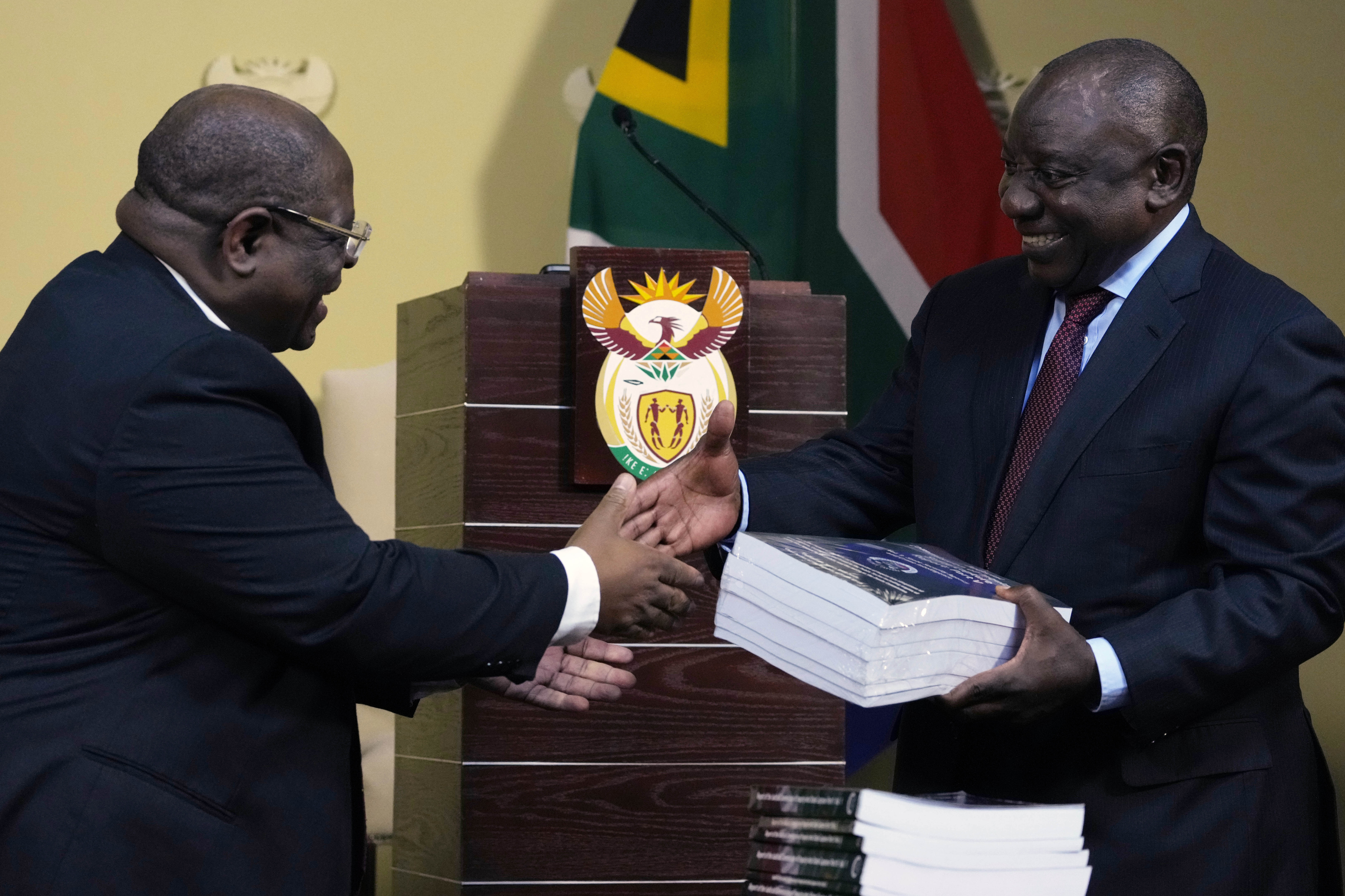 President Ramaphosa receives the final report of a judicial investigation into corruption from Chief Justice Raymond Zondo, left, at the Union Buildings in Pretoria on June 22, 2022
