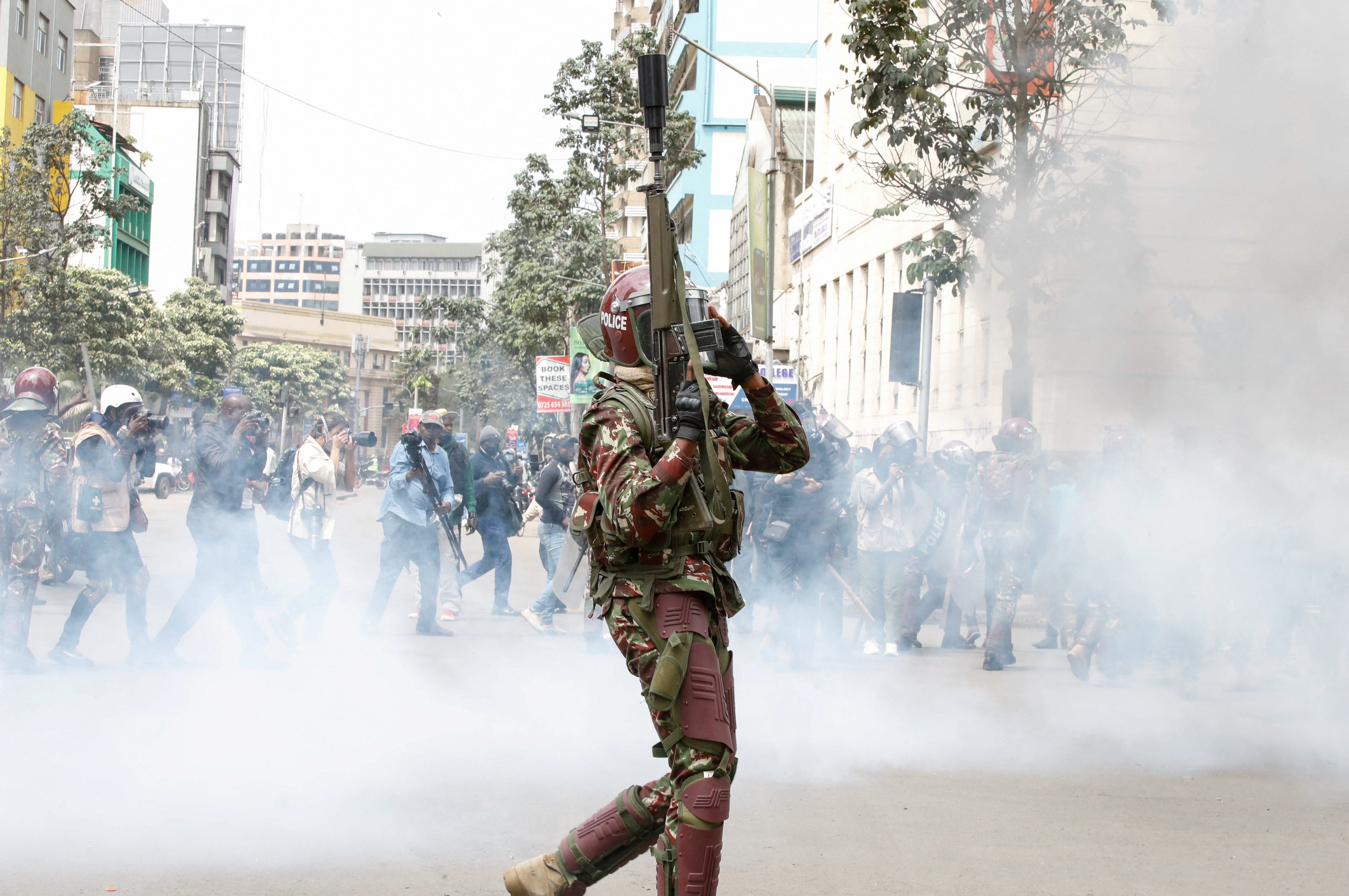 A Police member walks near a gas cloud at a demonstration over police killings of people protesting against Kenya's proposed finance bill