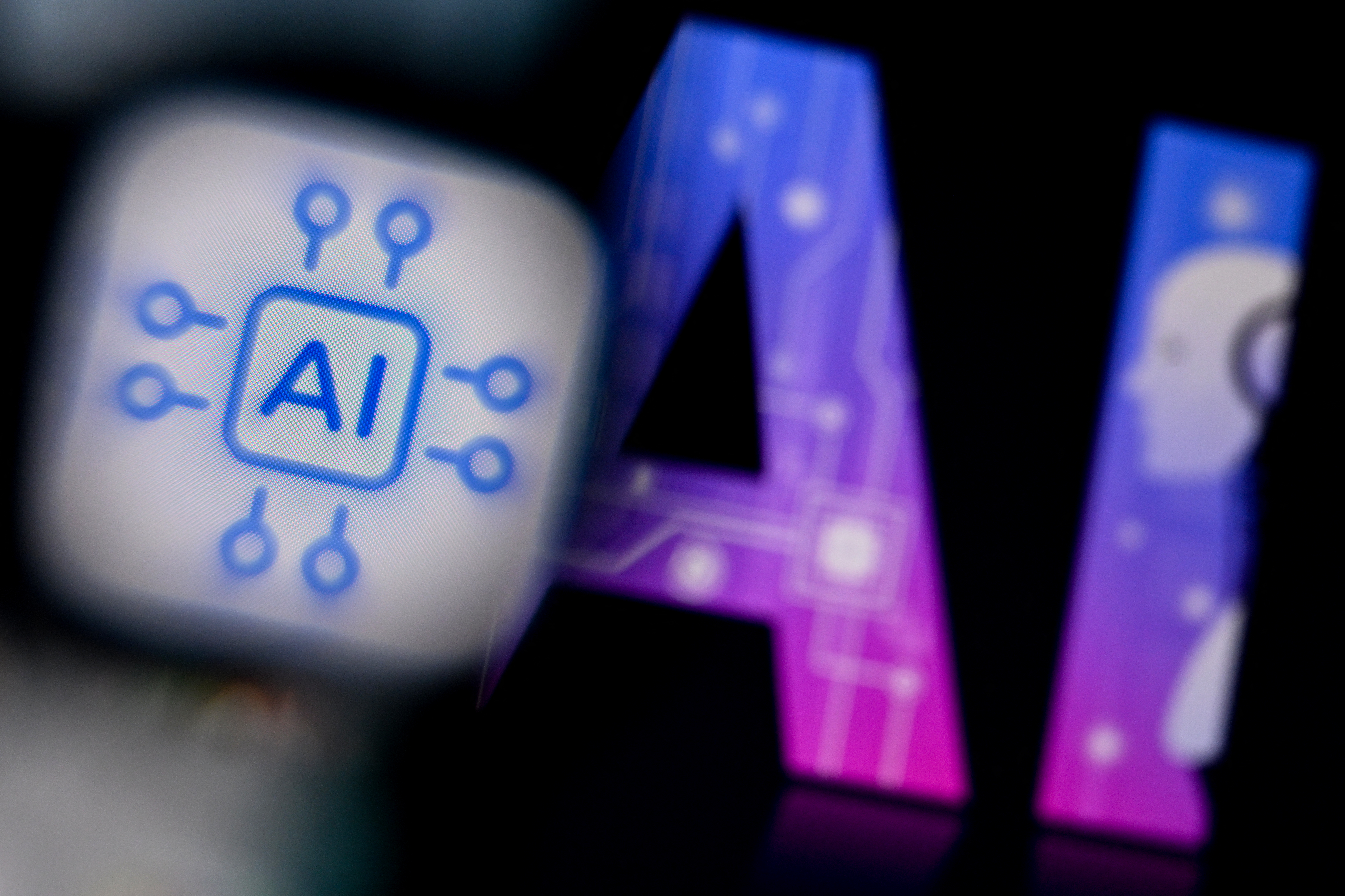 The logo of the Artificial Intelligence chat application on a smartphone screen (L) and and the letters AI on a laptop screen in Frankfurt am Main, western Germany