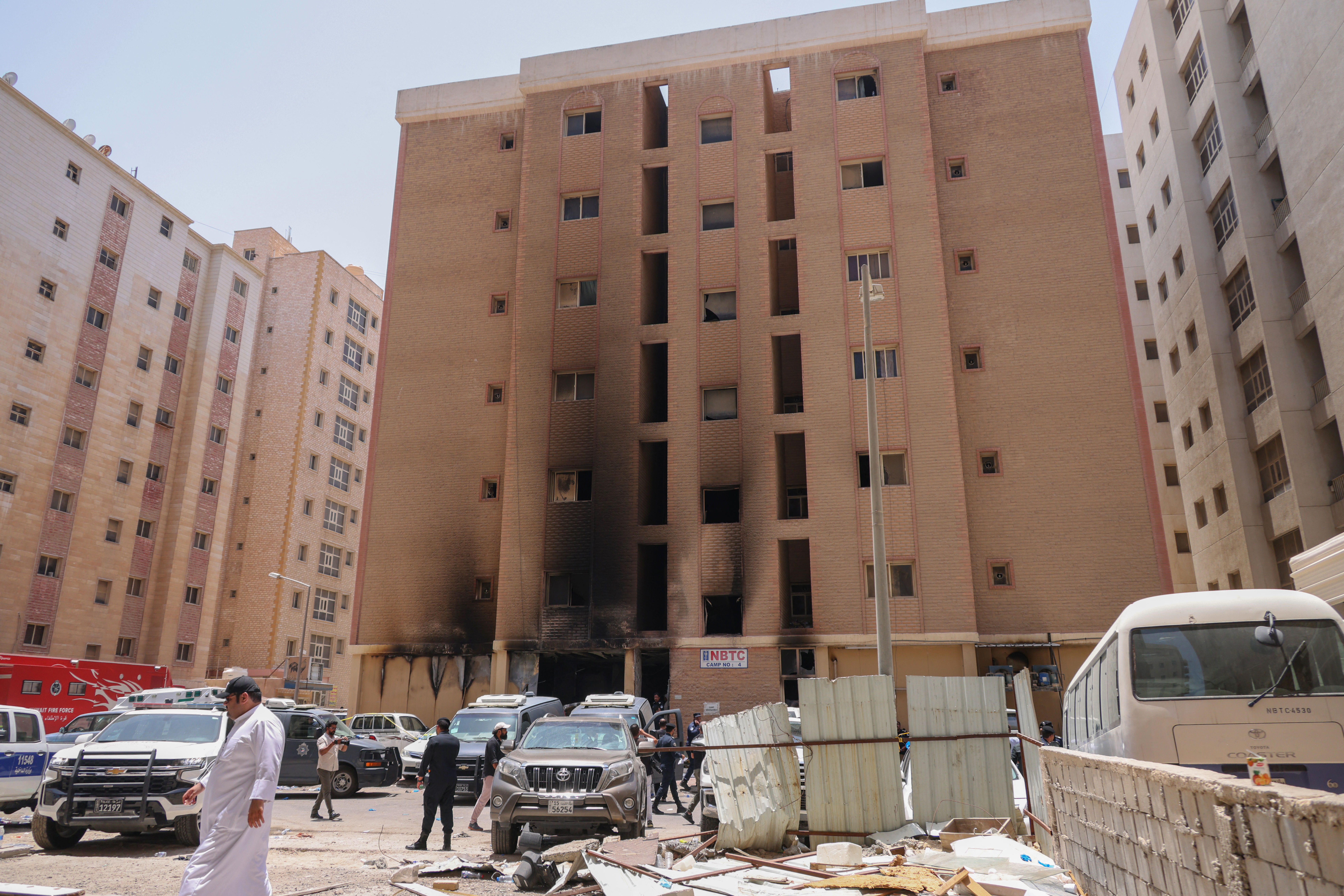 People walk past the building in Mangaf where the deadly fire took place