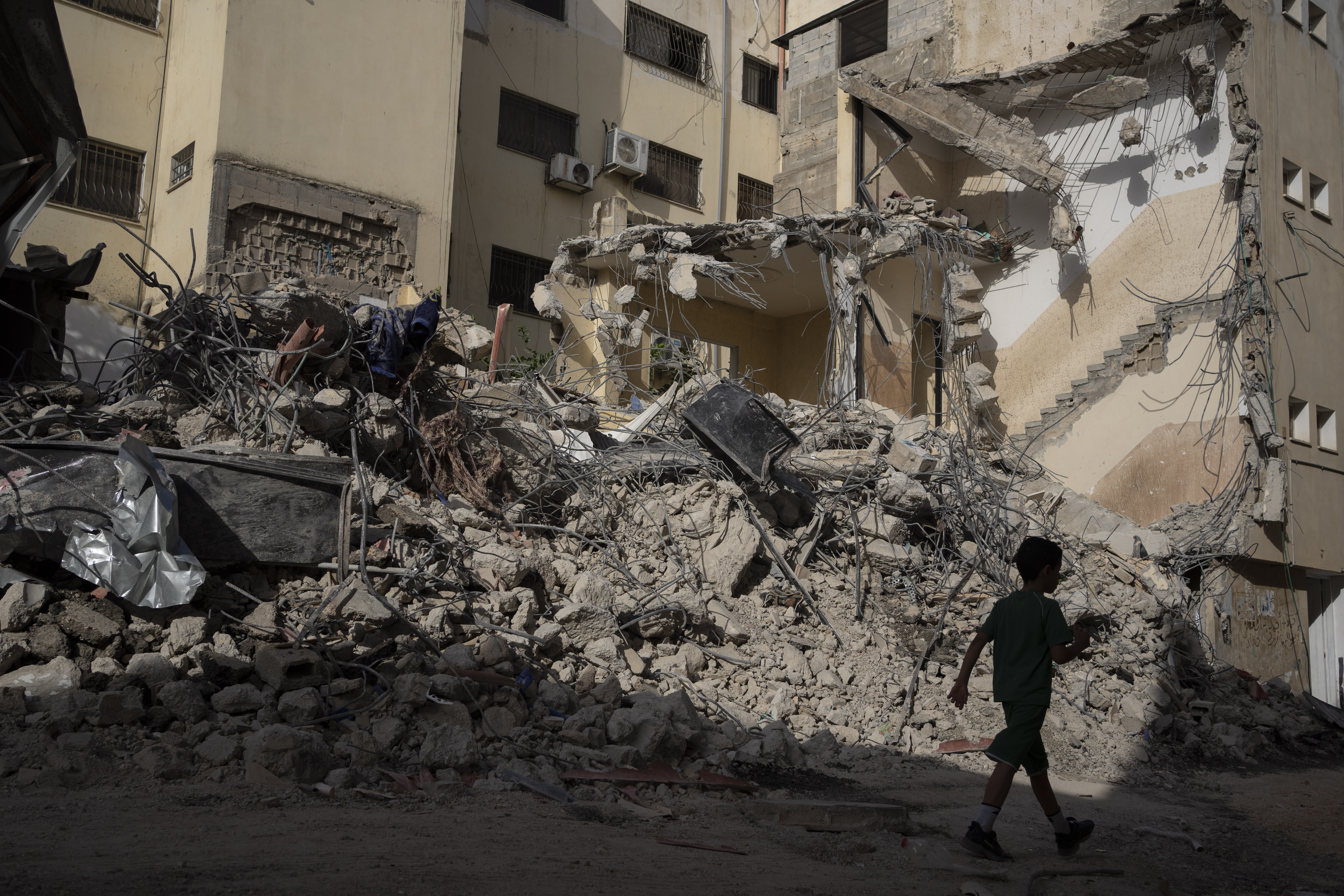 A boy walks past debris of a heavily damaged building after an Israeli forces raid in the West Bank city of Jenin, Thursday, May 23, 2024