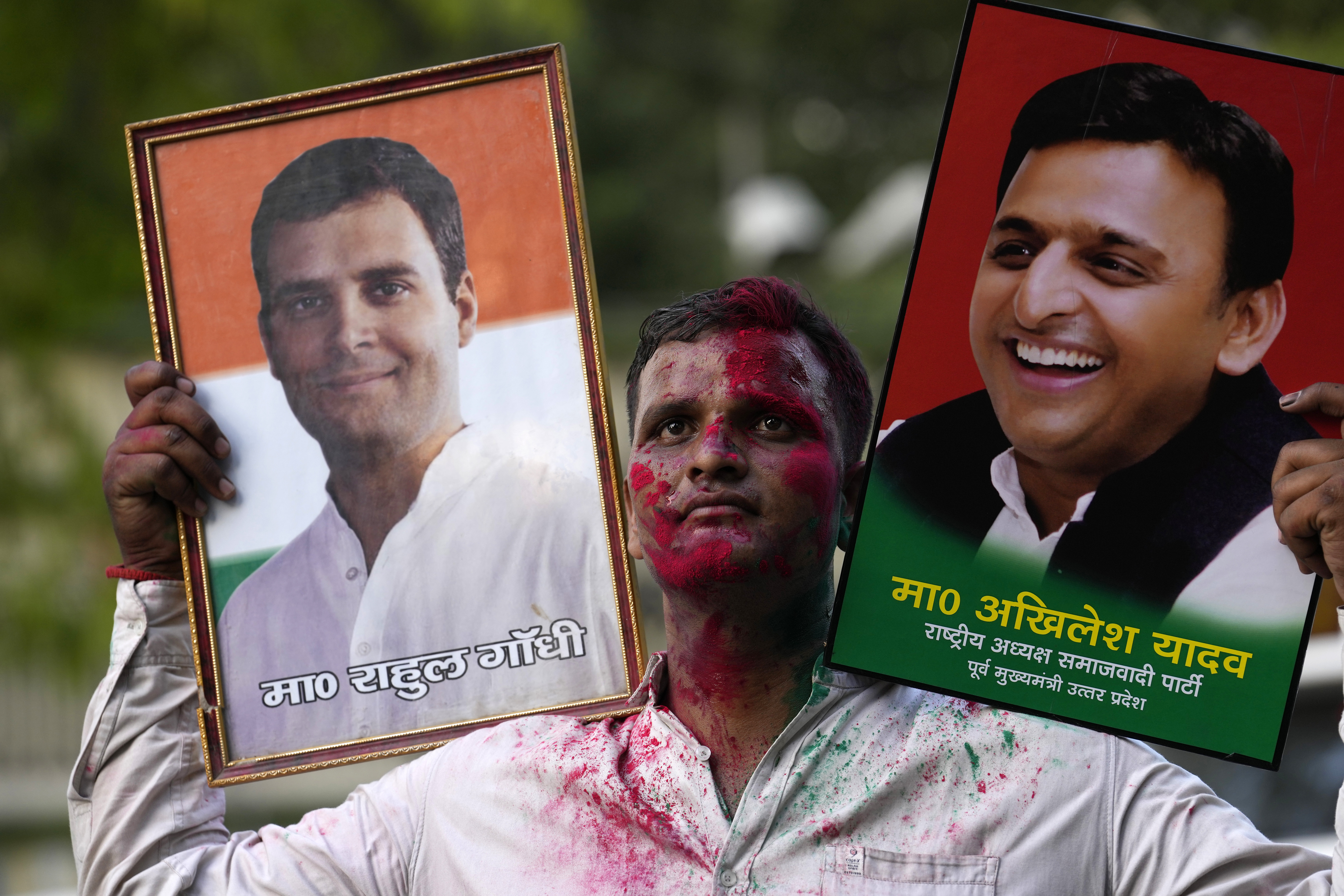 A Samajwadi Party supporter carries portraits of party leader Akhilesh Yadav, right, and Congress Party leader, Rahul Gandhi, as he celebrates his party’s lead during the counting of votes in India’s national election in Lucknow, India