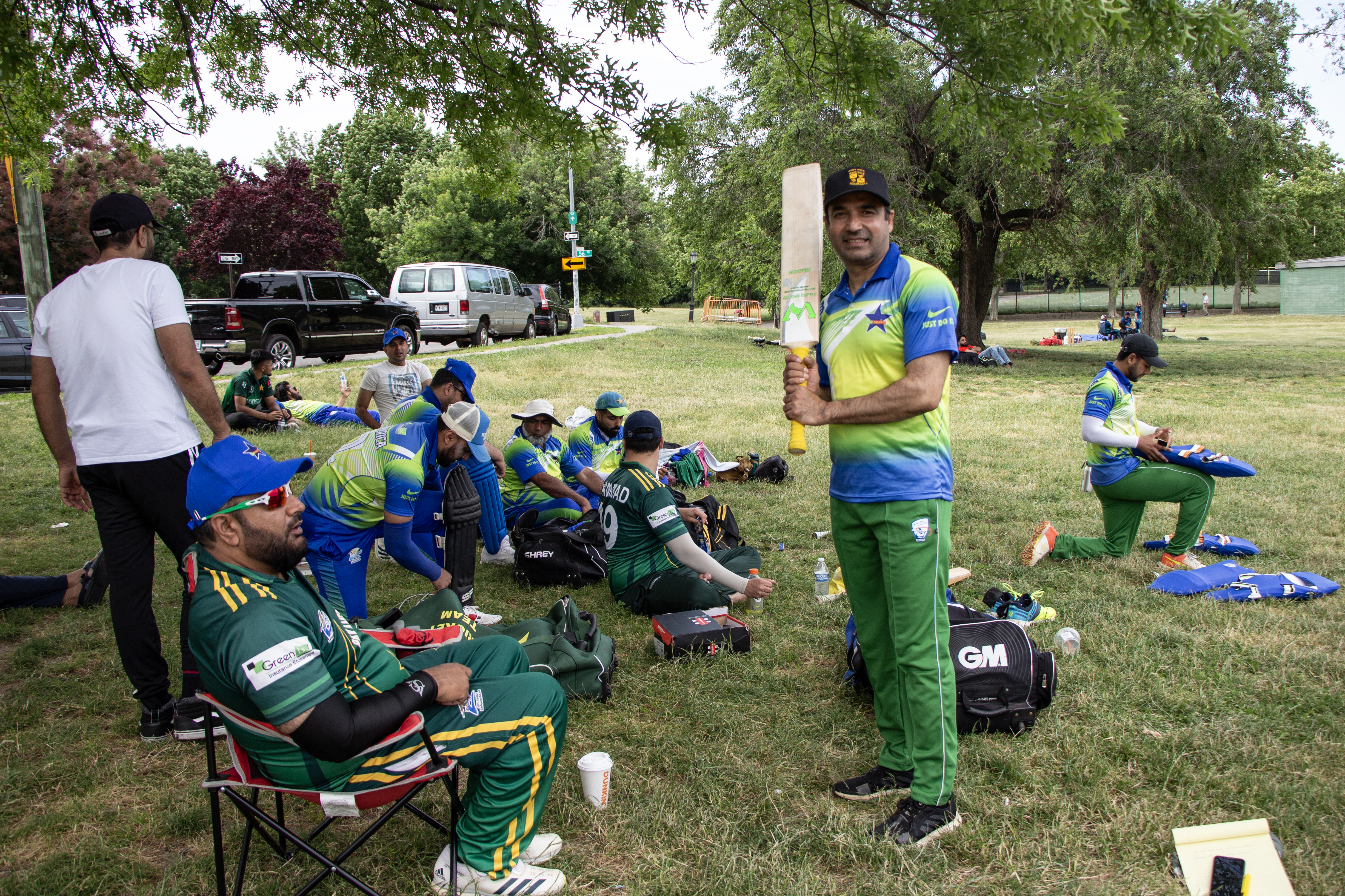 PakAmerica Cricket Club’s captain Anjum Sabar, left, watches the players on the field as Sarmad Khan, right, holds up his bat towards the end of a match in New York
