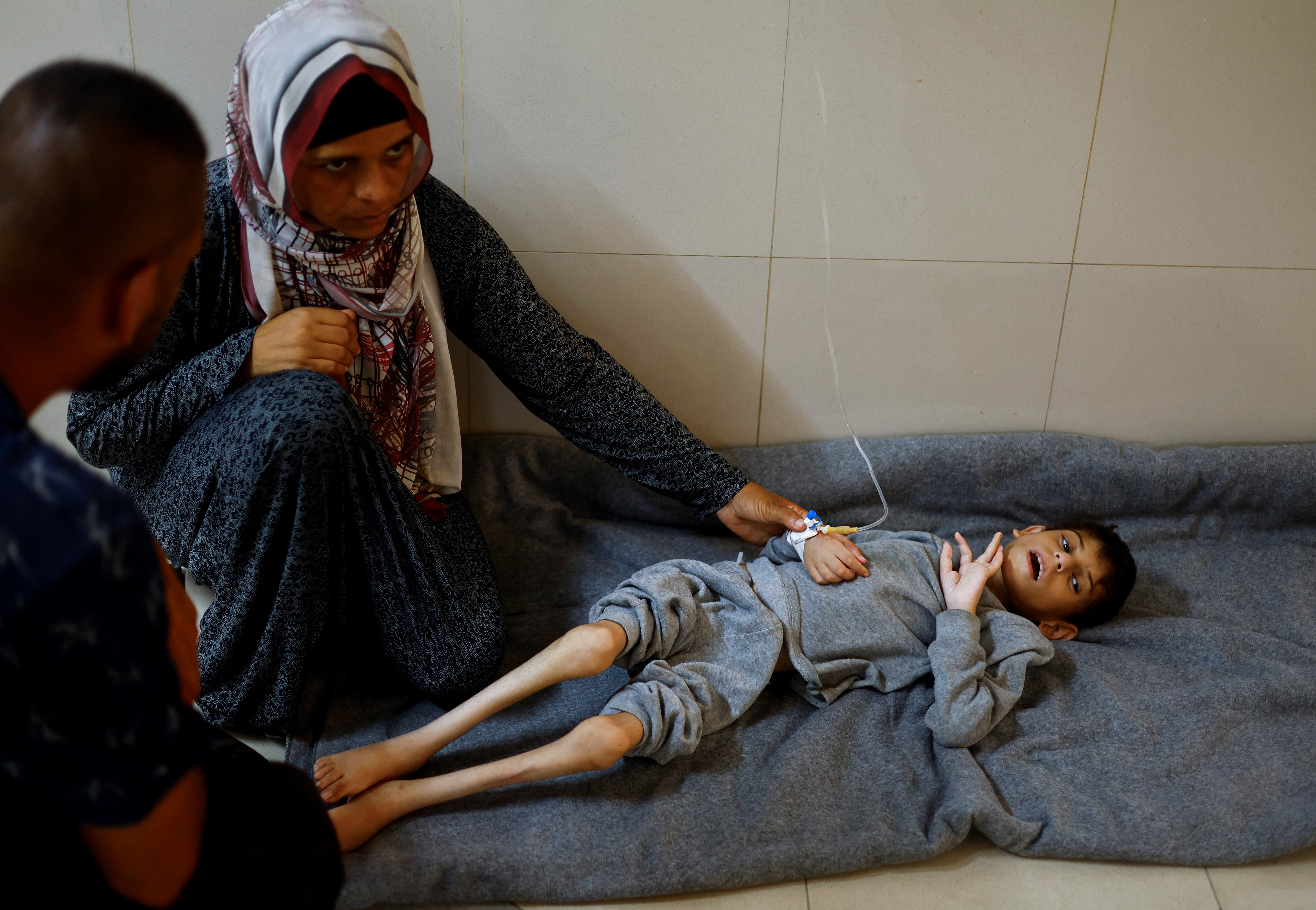 Palestinian mother Ghaneyma Joma sits next to her malnourished son Younis Joma as he receives treatment at Nasser hospital in Khan Younis