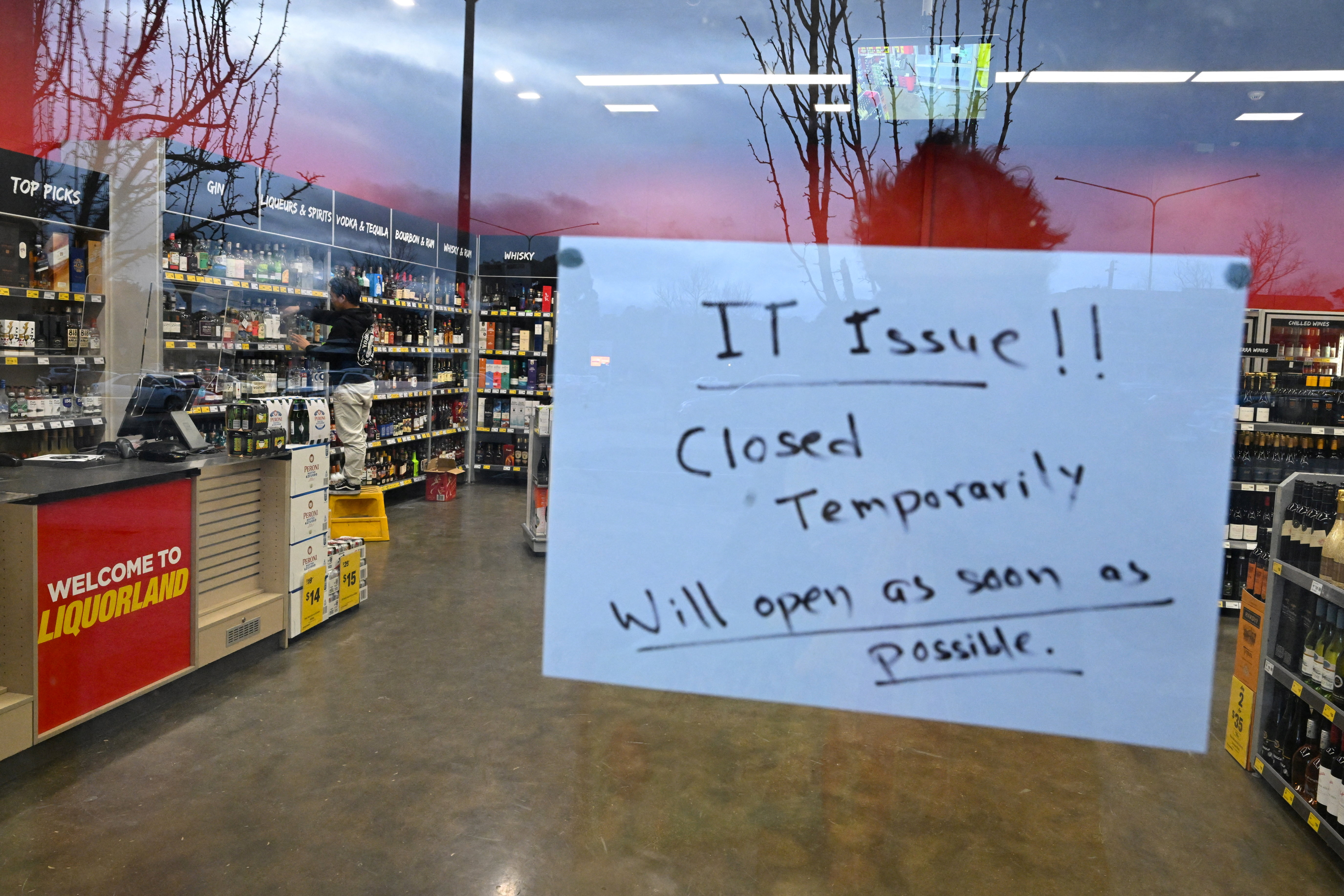A sign notifies customers of a temporary closure due to IT issues at a Liquorland store in Canberra, Australia, July 19