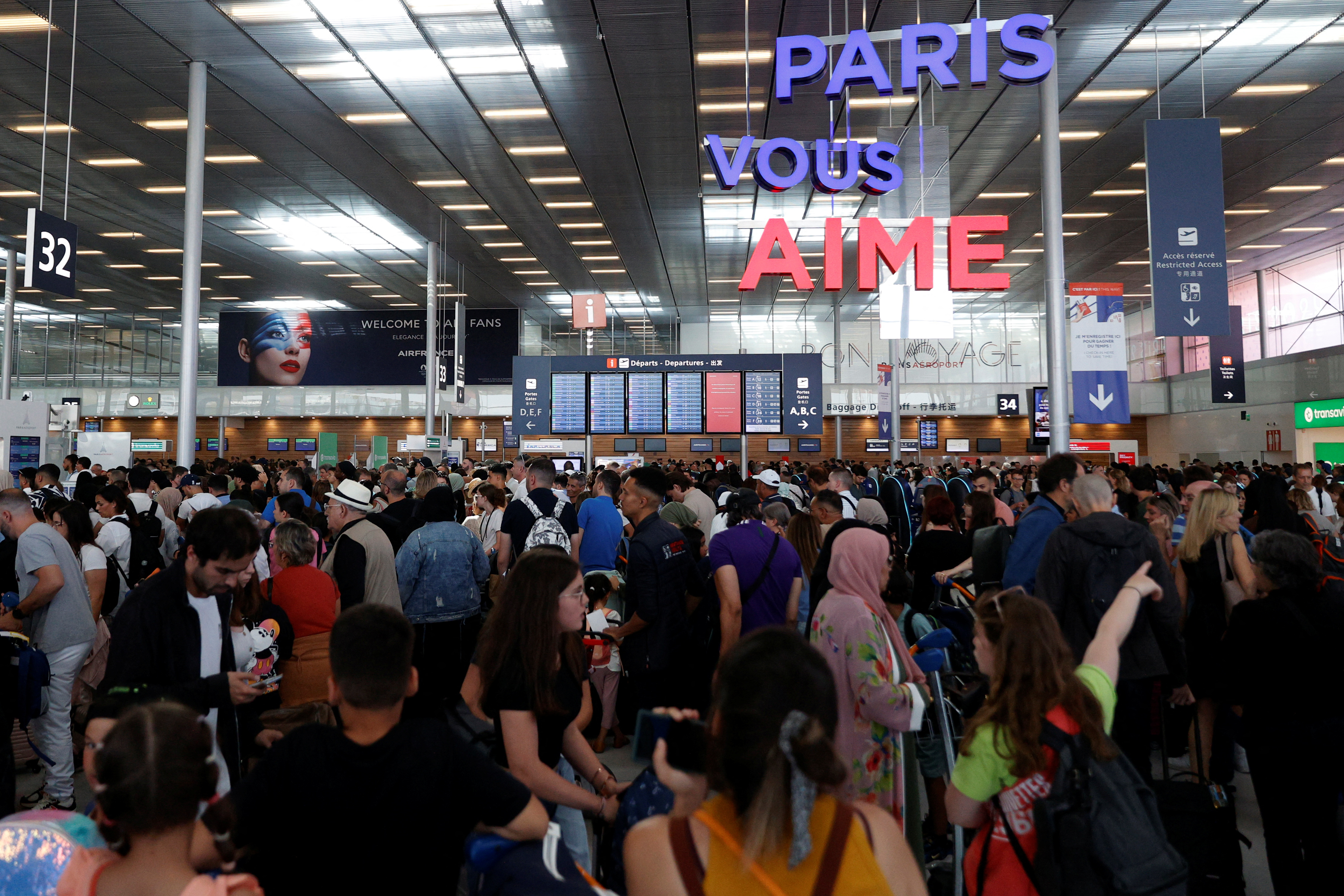 Passengers wait inside the Terminal 3 as operations have been disrupted following a global IT issue